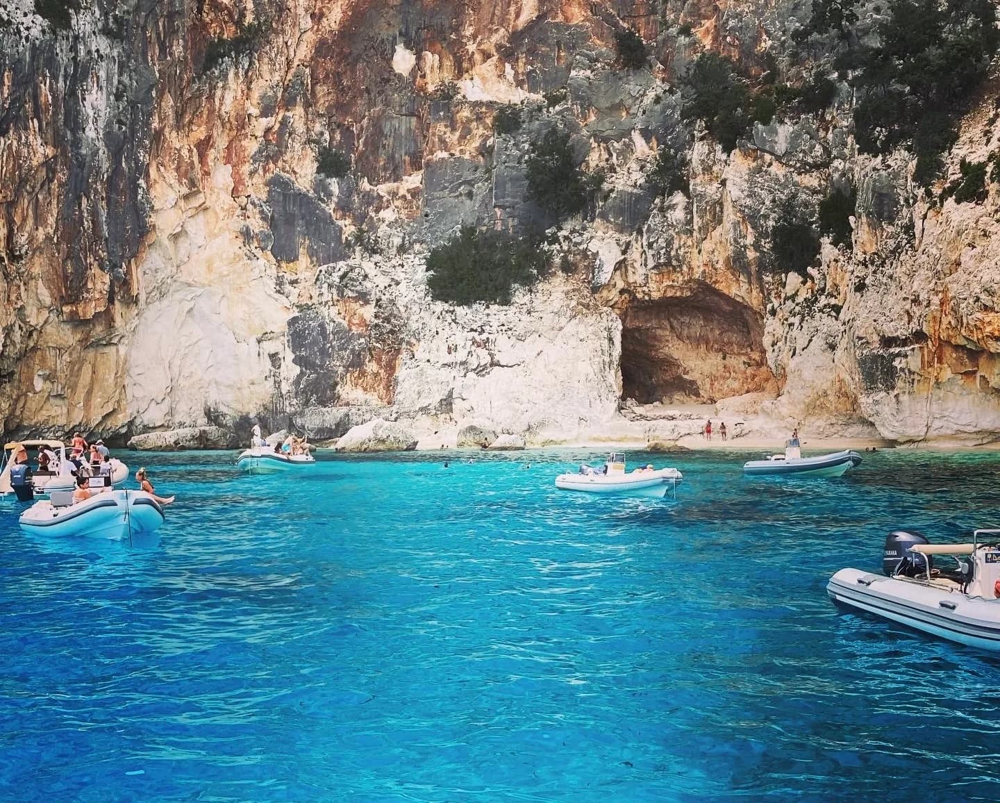 Bateaux sur une eau turquoise près de falaises côtières.