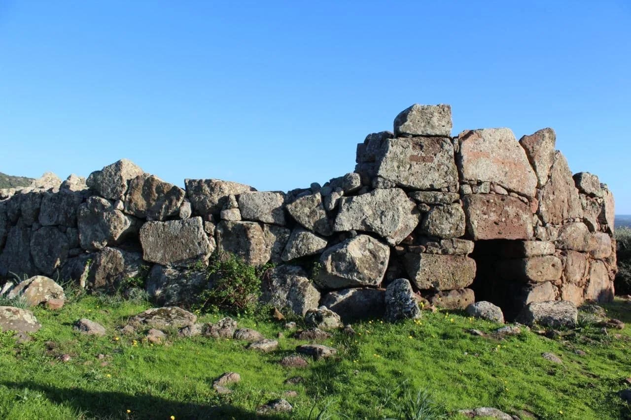 Visitors exploring Monte Baranta’s prehistoric walls under blue Sardinian skies