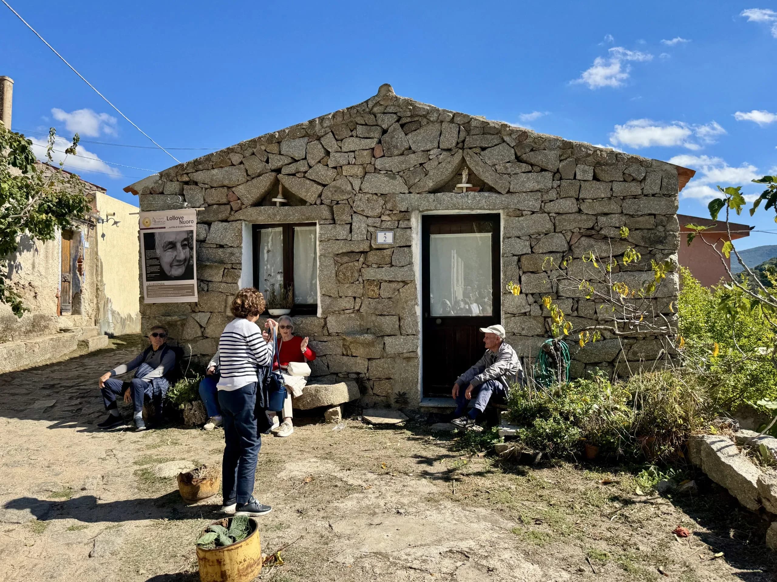 Menschen im Gesprach vor einem rustikalen Steinhaus