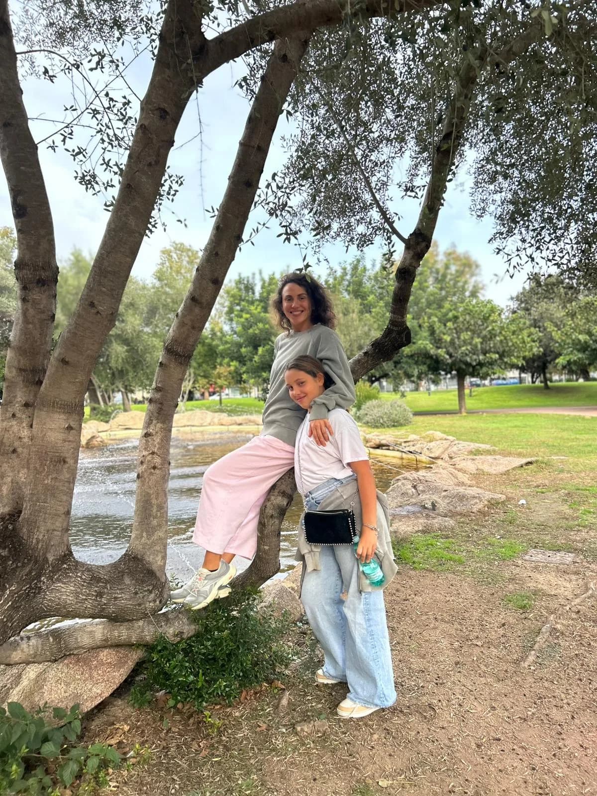 Mother and daughter at park near tree.