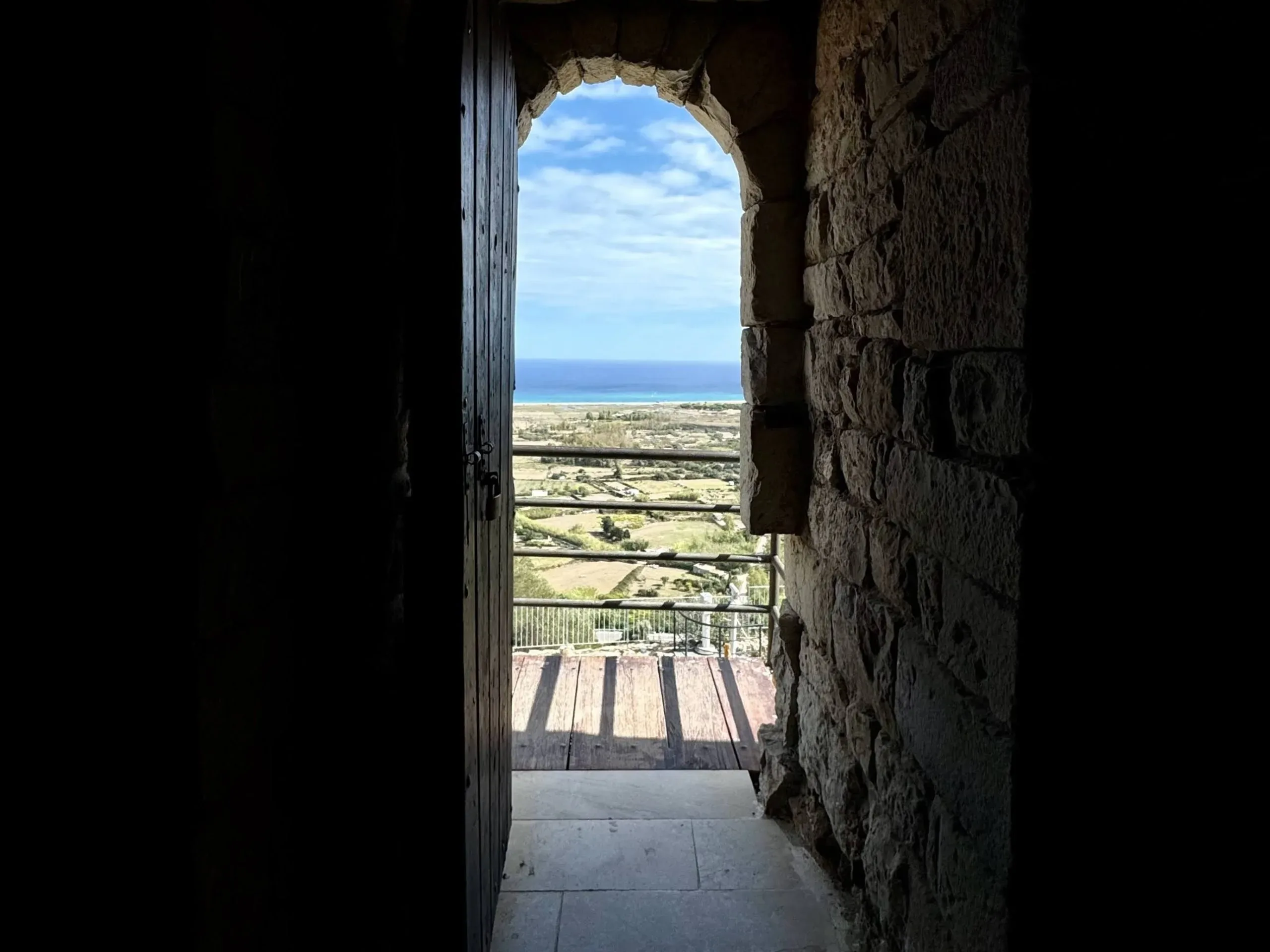 Blick durch einen Steinbogen auf Meer und Landschaft.
