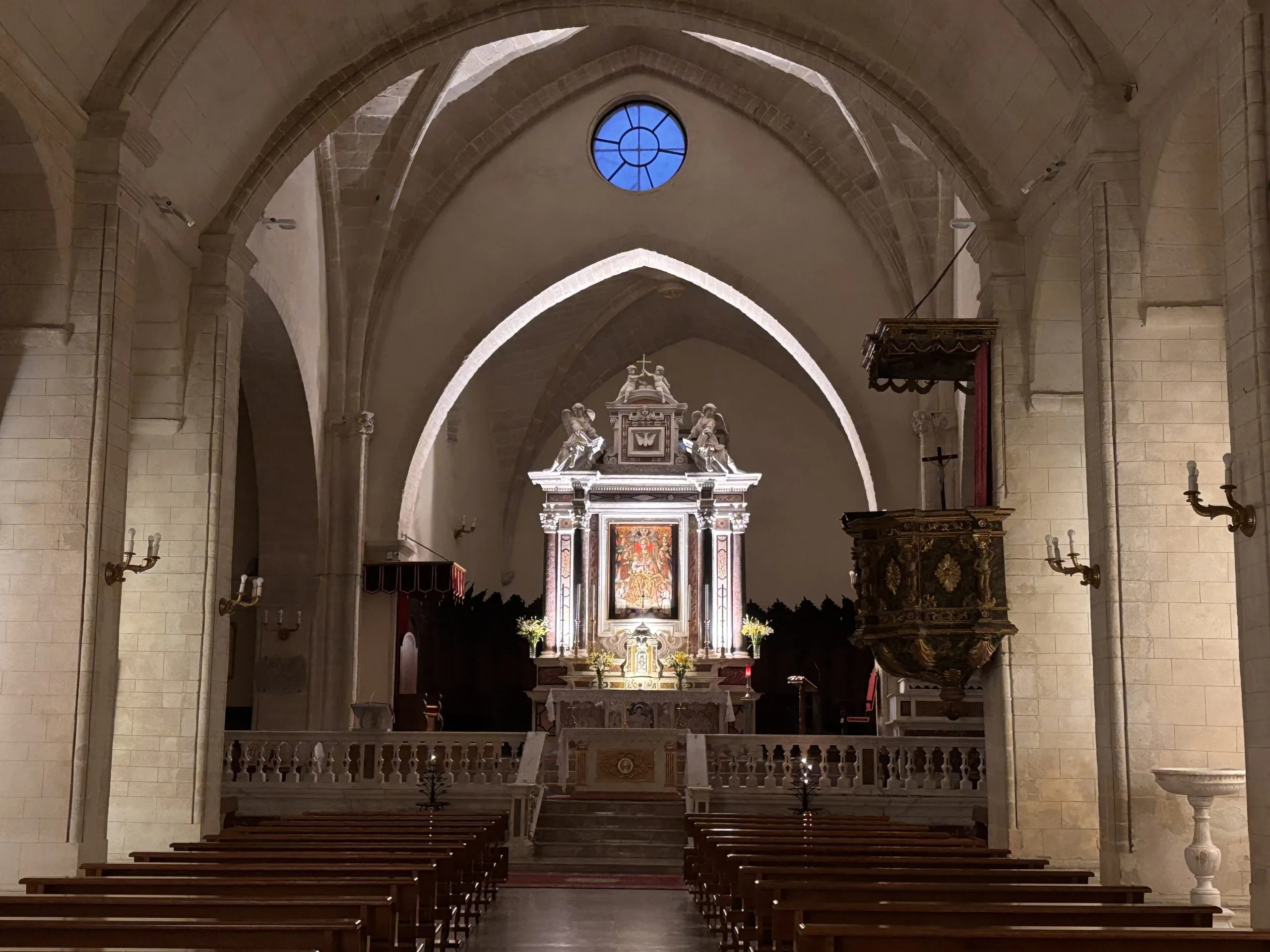 Interno di chiesa con banchi, altare e archi.