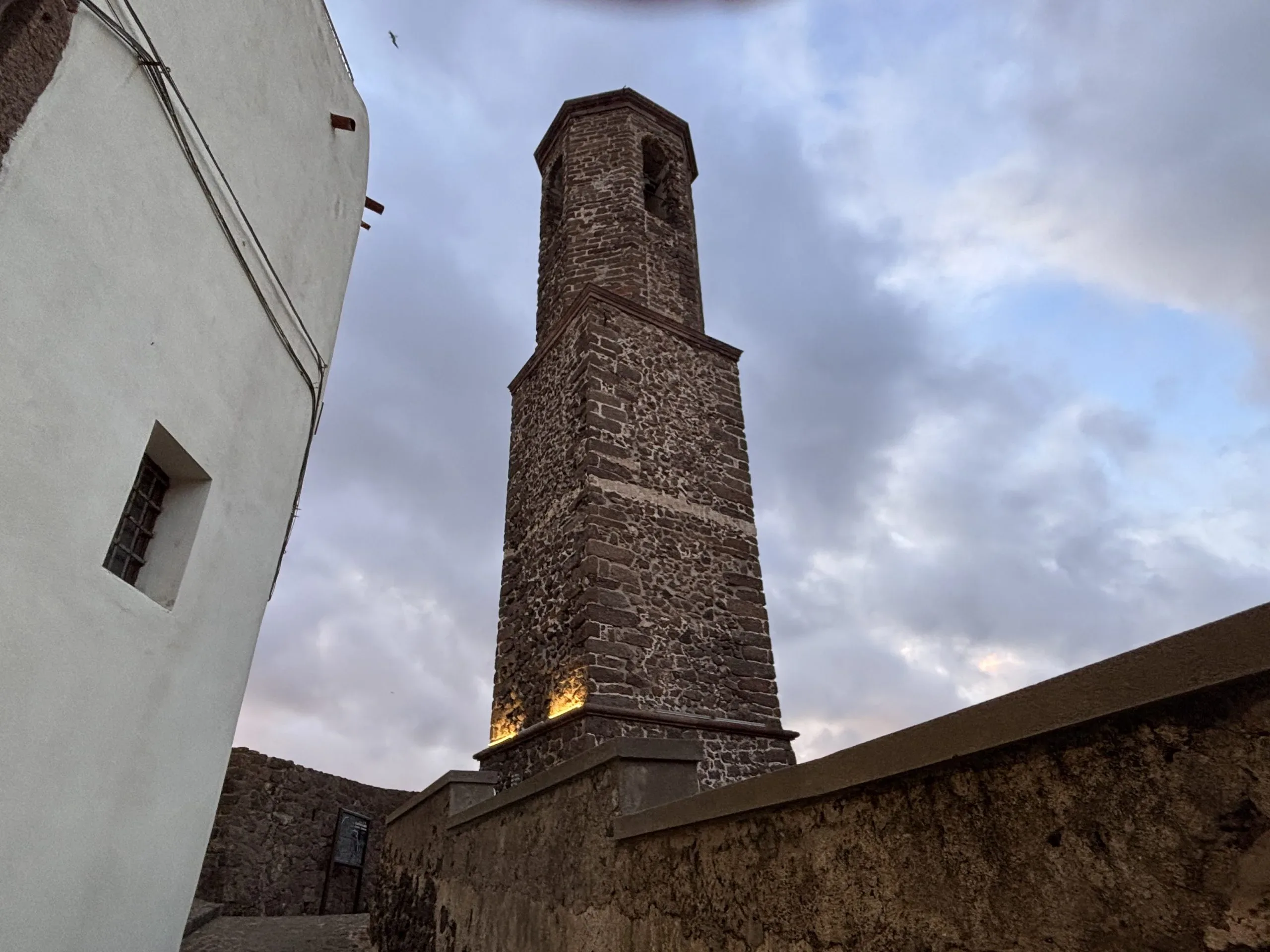 Torre in pietra contro un cielo nuvoloso, dettaglio architettonico.