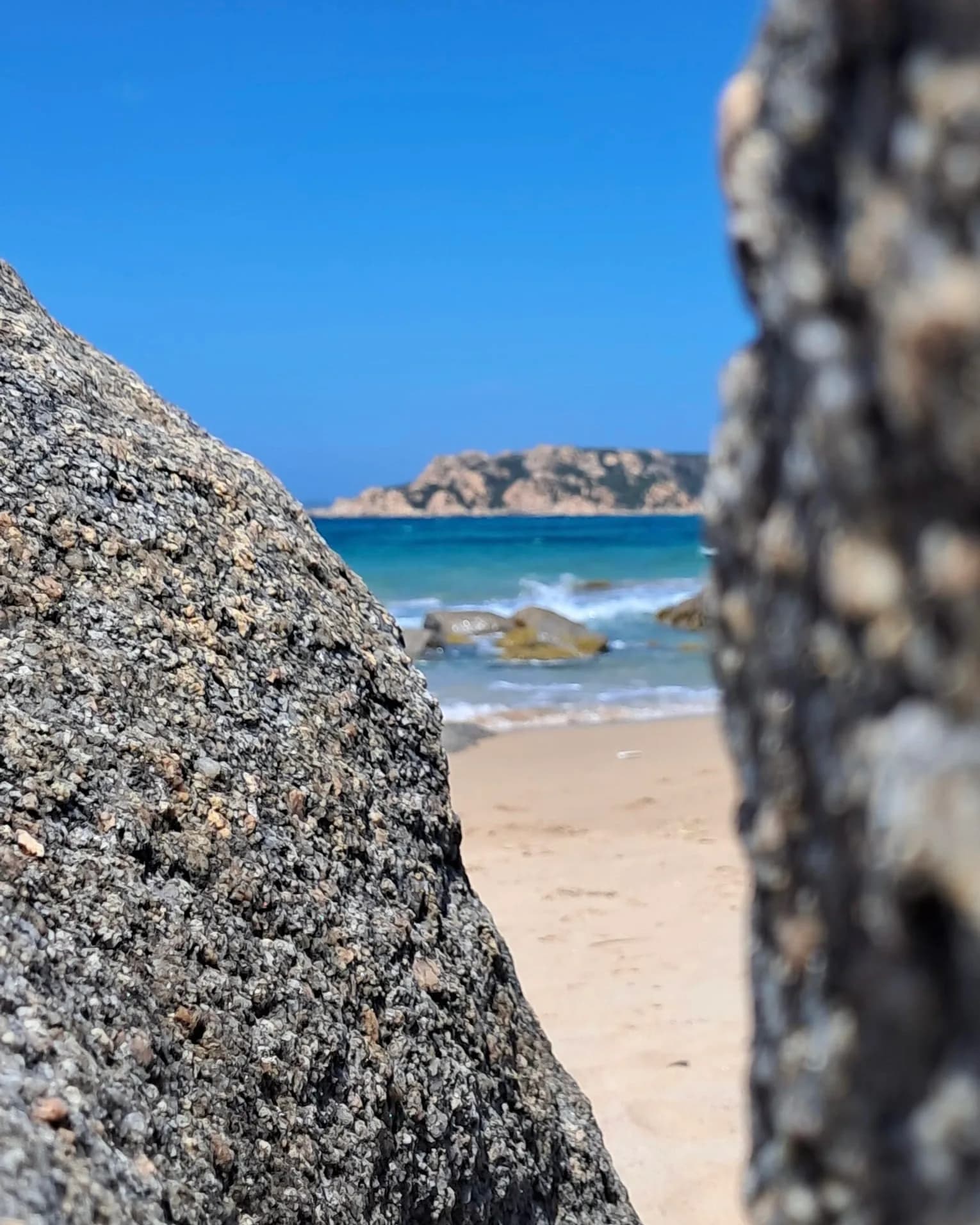 Scène de plage encadrée par des rochers côtiers