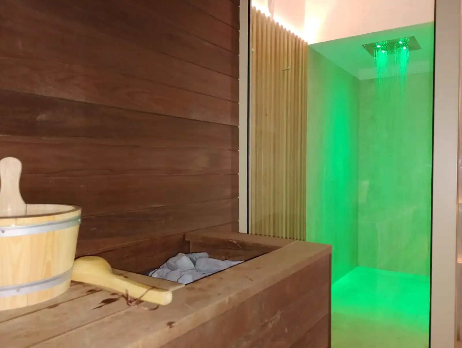 Sauna with wooden bucket and green shower.