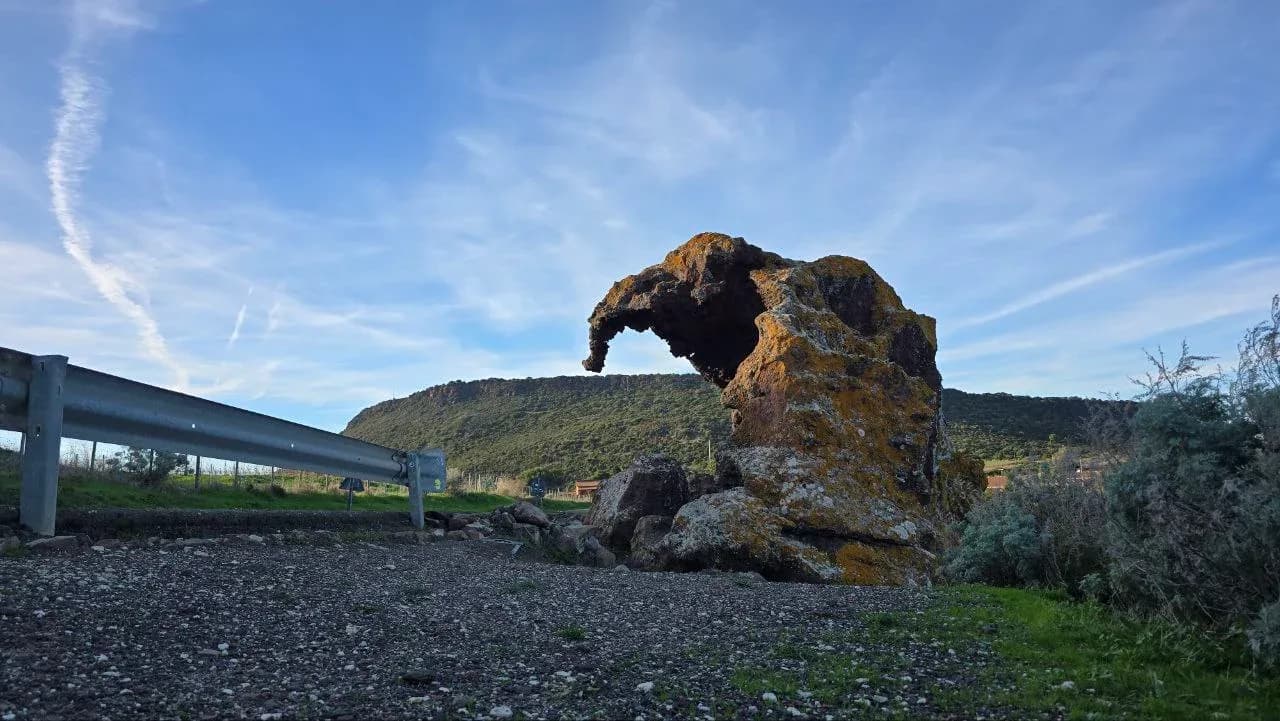 Elephant rock formation near road, blue sky.