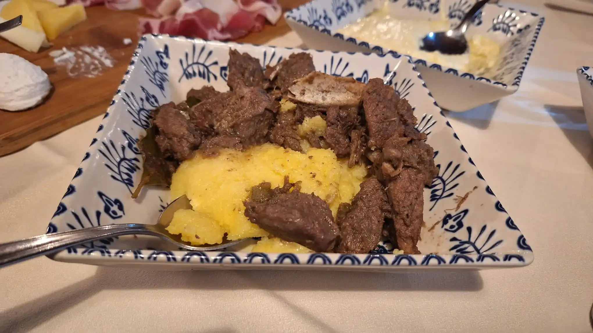 Polenta en vleesgerecht op gepatroneerd bord.
