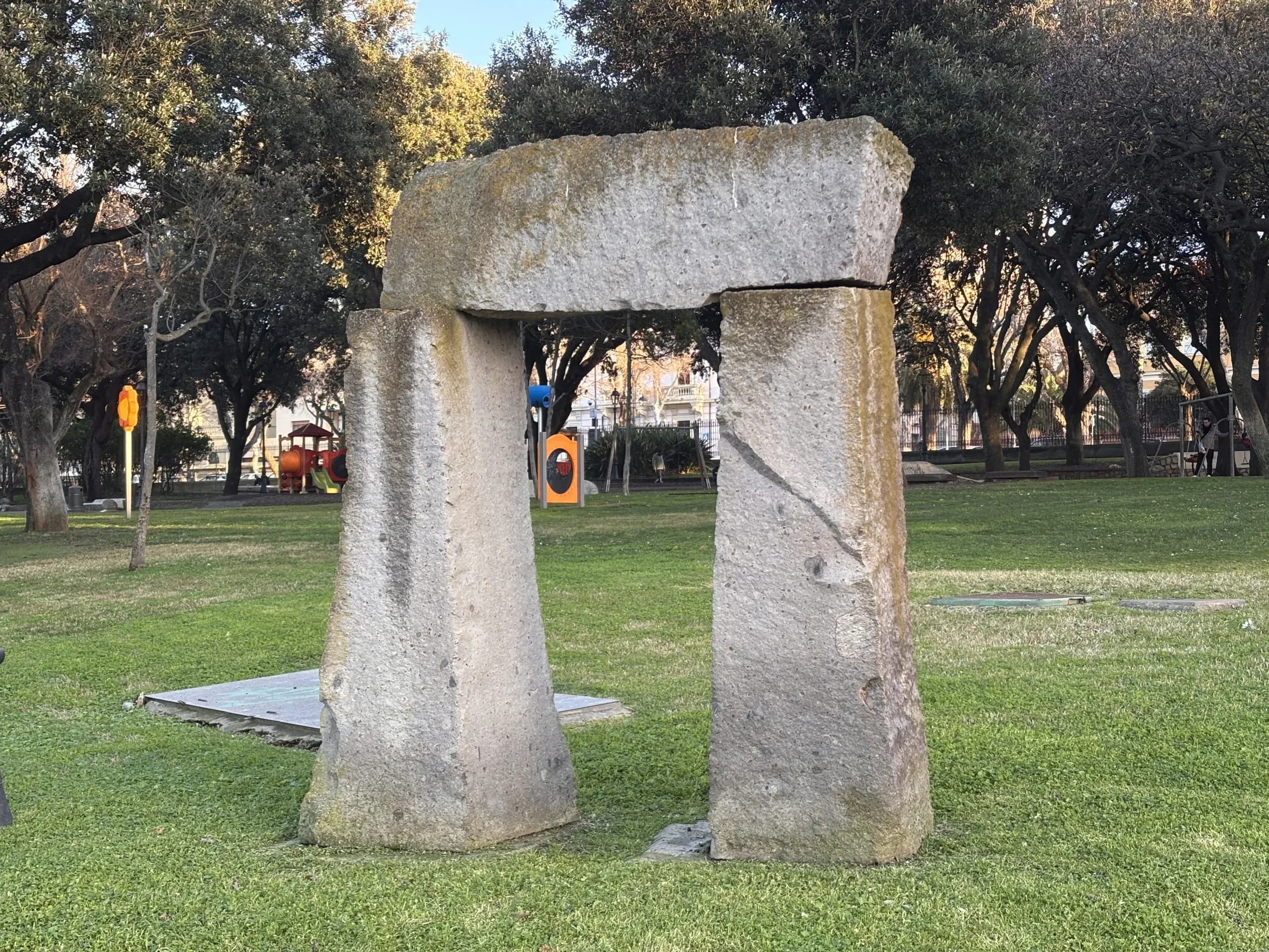 Arche en pierre dans un parc sur une pelouse.