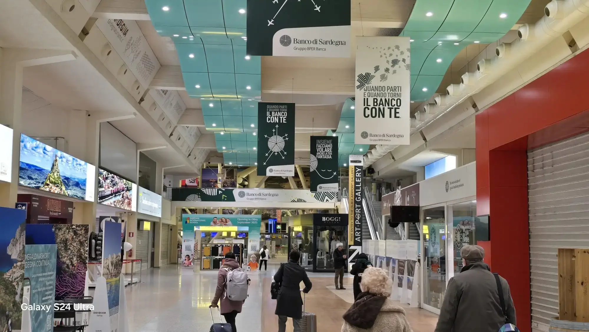 Reisende gehen durch das Terminal des Flughafens Olbia