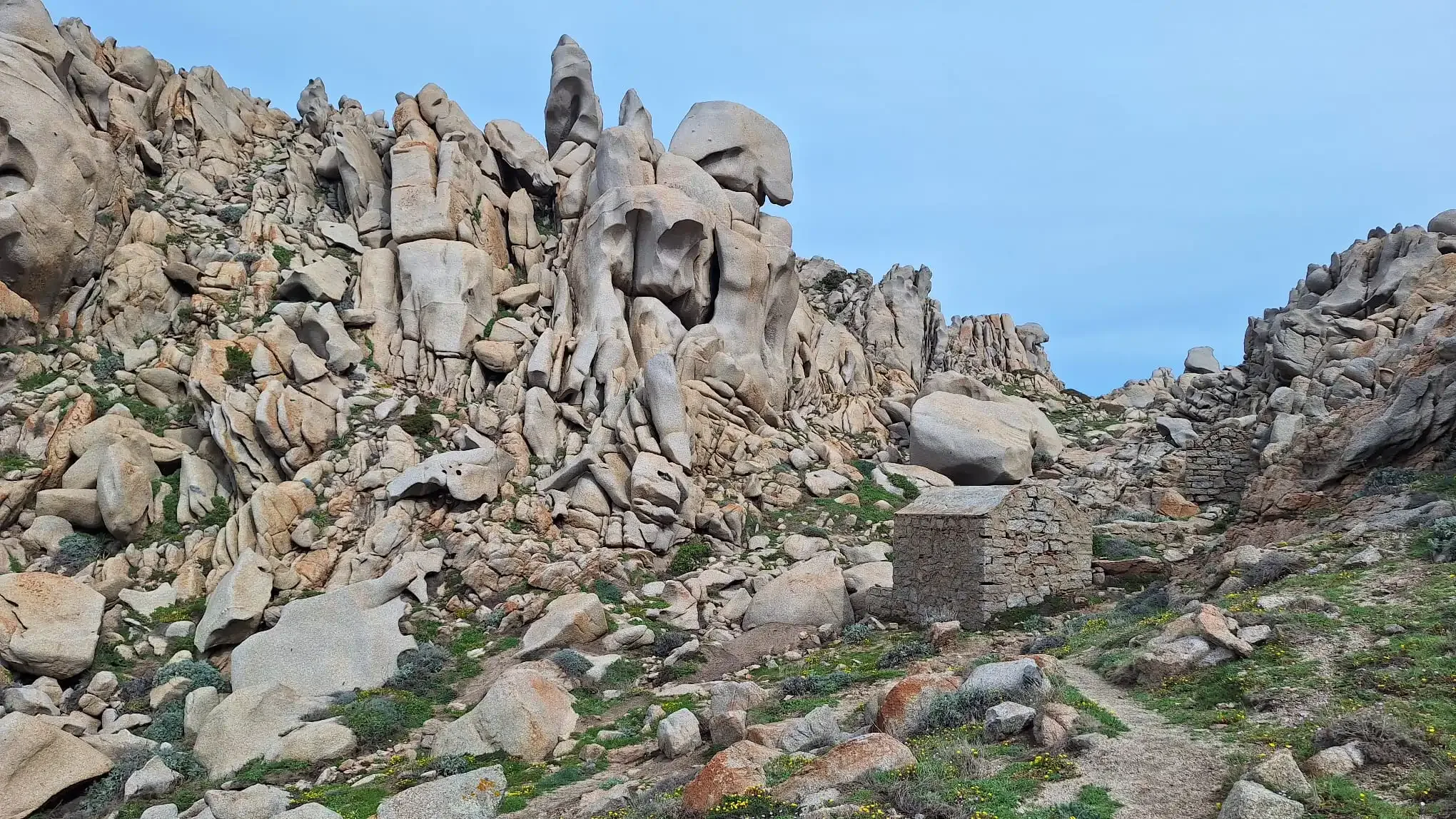 Felsformationen und Steinhütte auf felsigem Hügel.