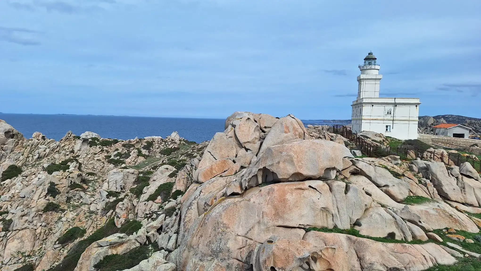 Weißer Leuchtturm an felsiger Küste mit Blick auf das Meer