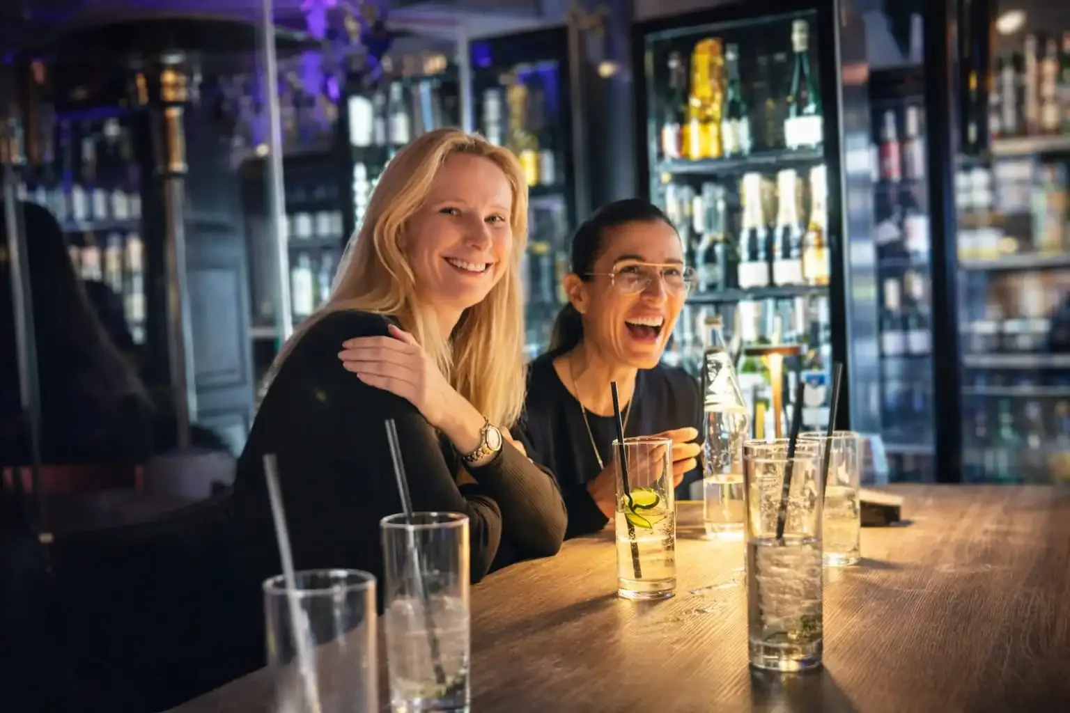 Two women laughing at a bar