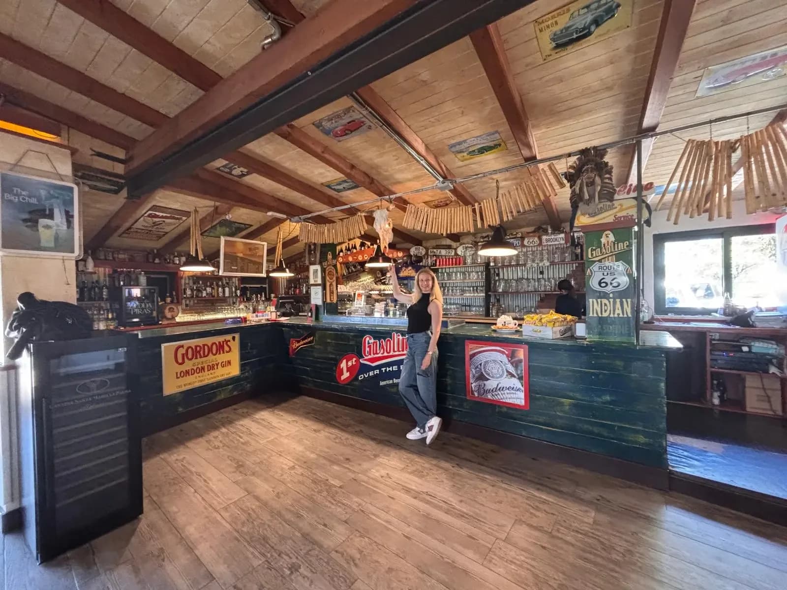 Femme dans un bar rétro avec enseignes et décorations vintage.