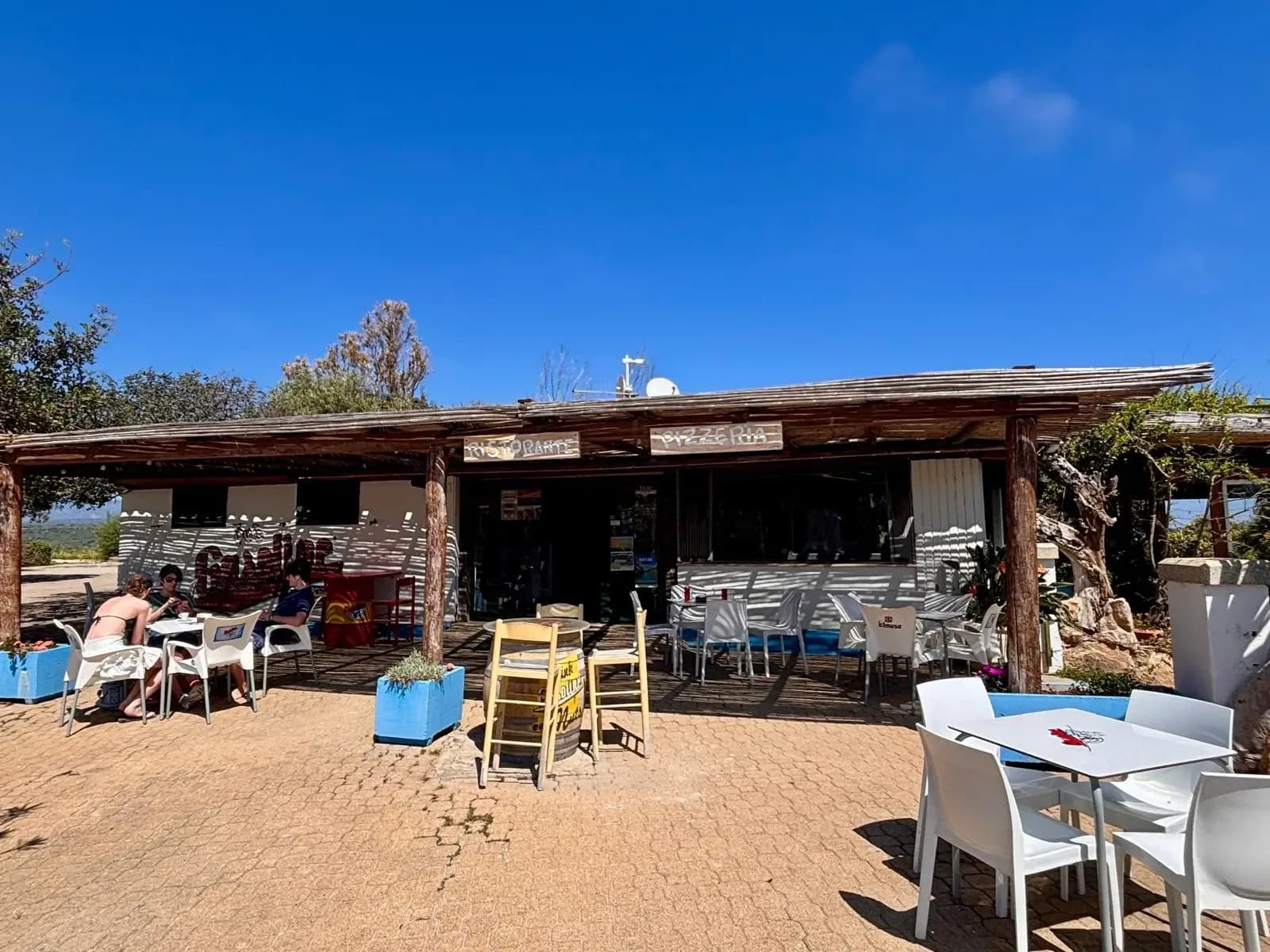 Restaurant ou pizzeria en extérieur avec terrasse sous un ciel lumineux.