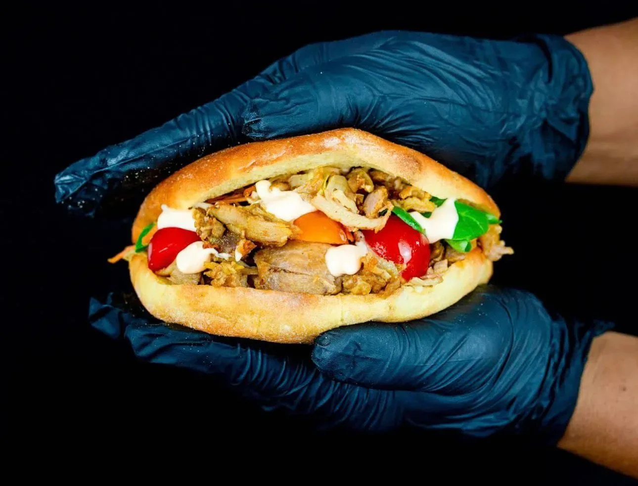 Doner kebab sandwich in black gloved hands