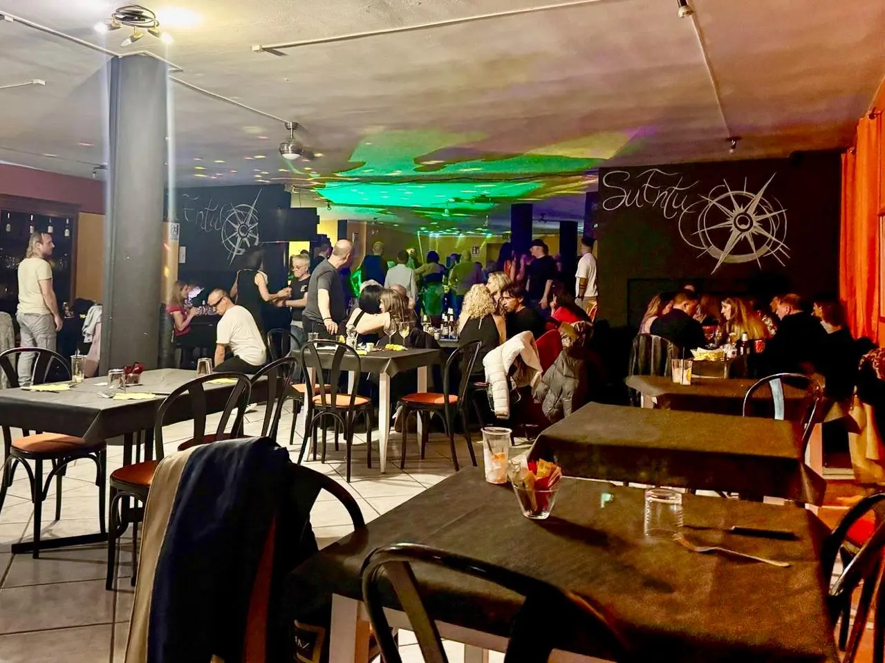 Restaurant scene with patrons dining and dancing.