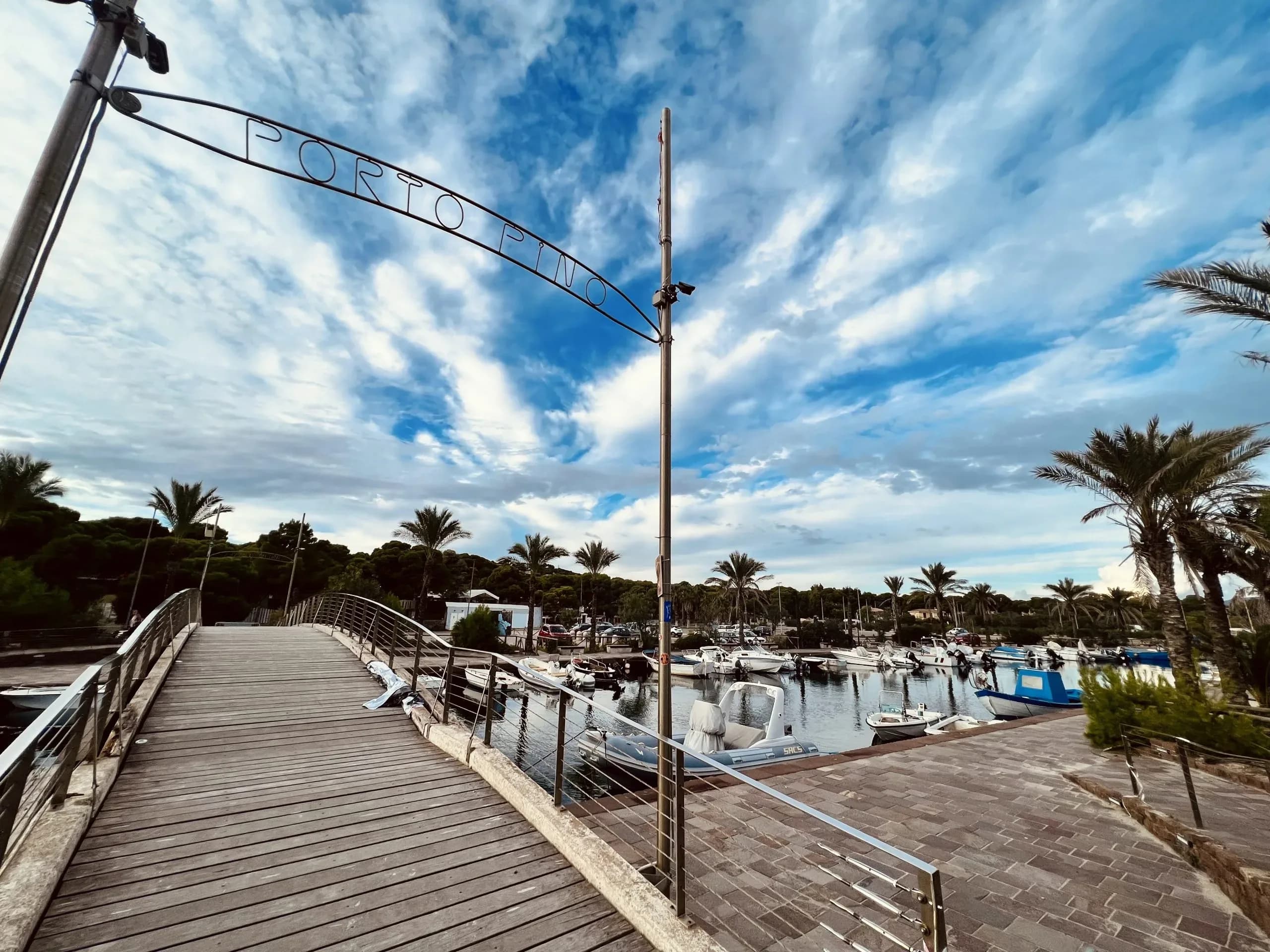 Porto Pino marina view with boats and blue sky.