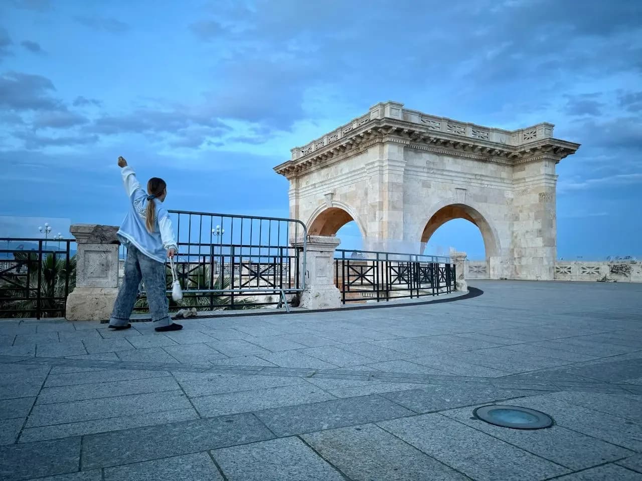 Young woman at Triumphal Arch of Cagliari at sunset.