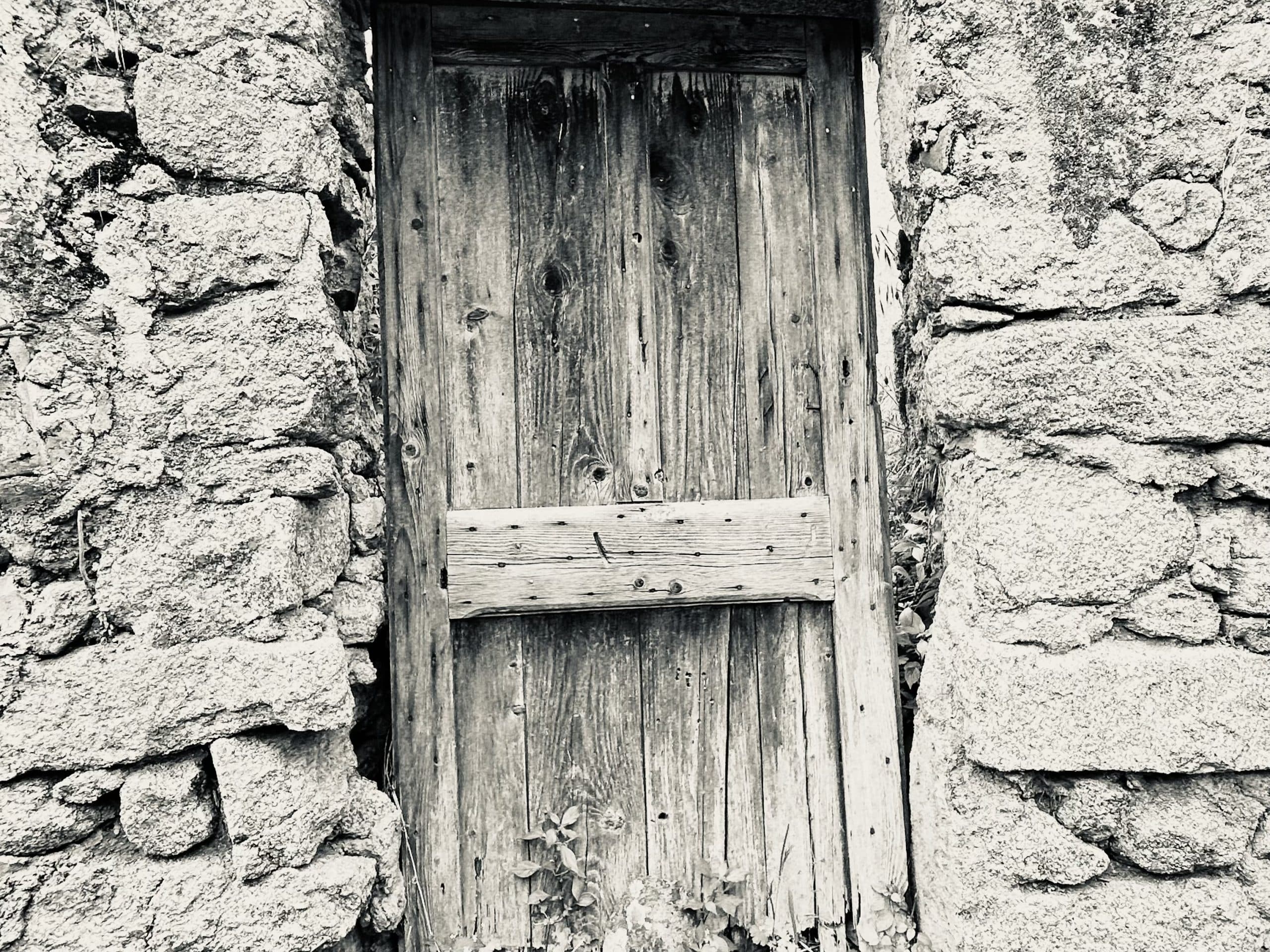 Porte en bois patiné entre des murs de pierre brute