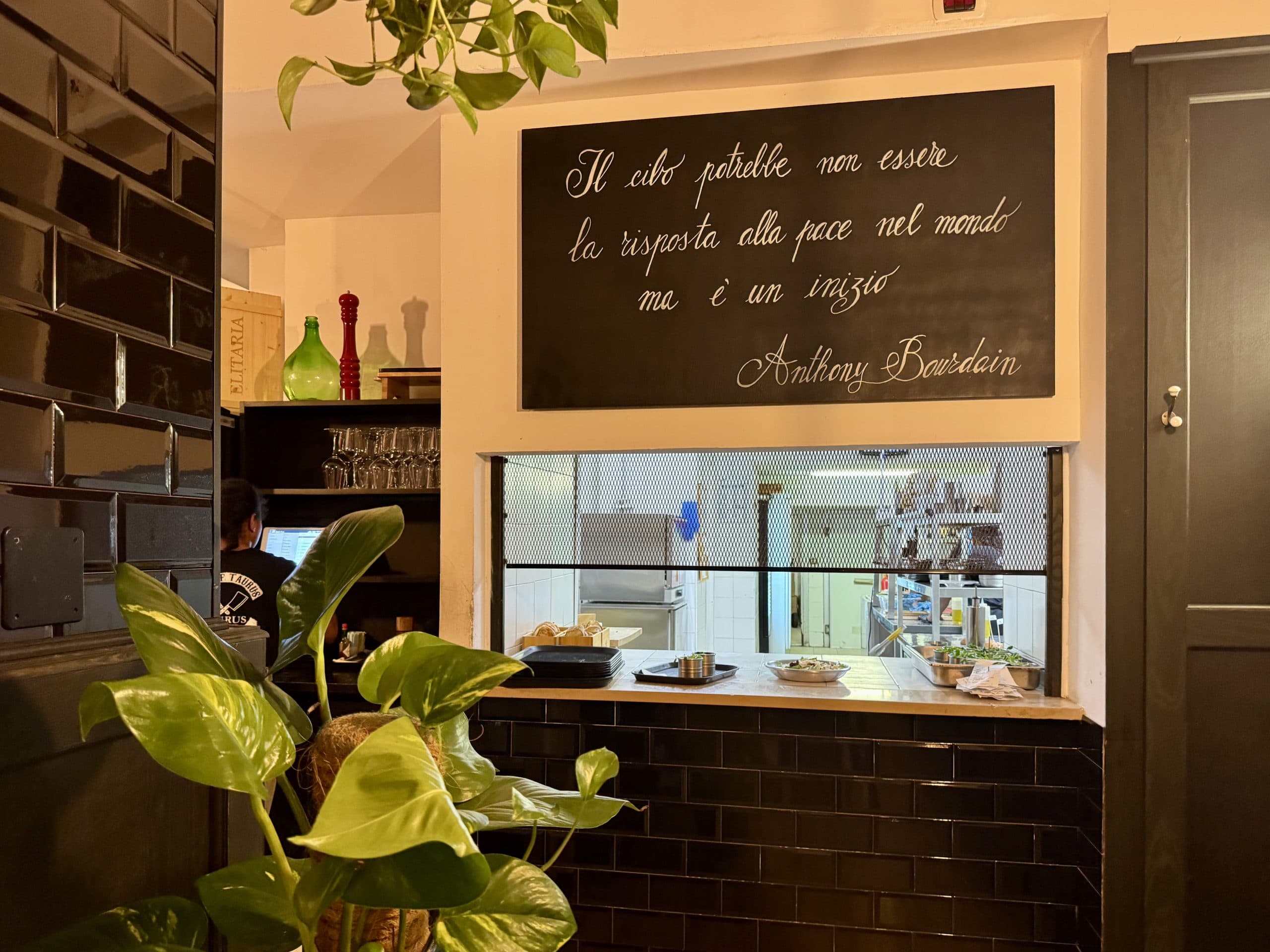 Interno di ristorante con cartello riportante una citazione di Anthony Bourdain