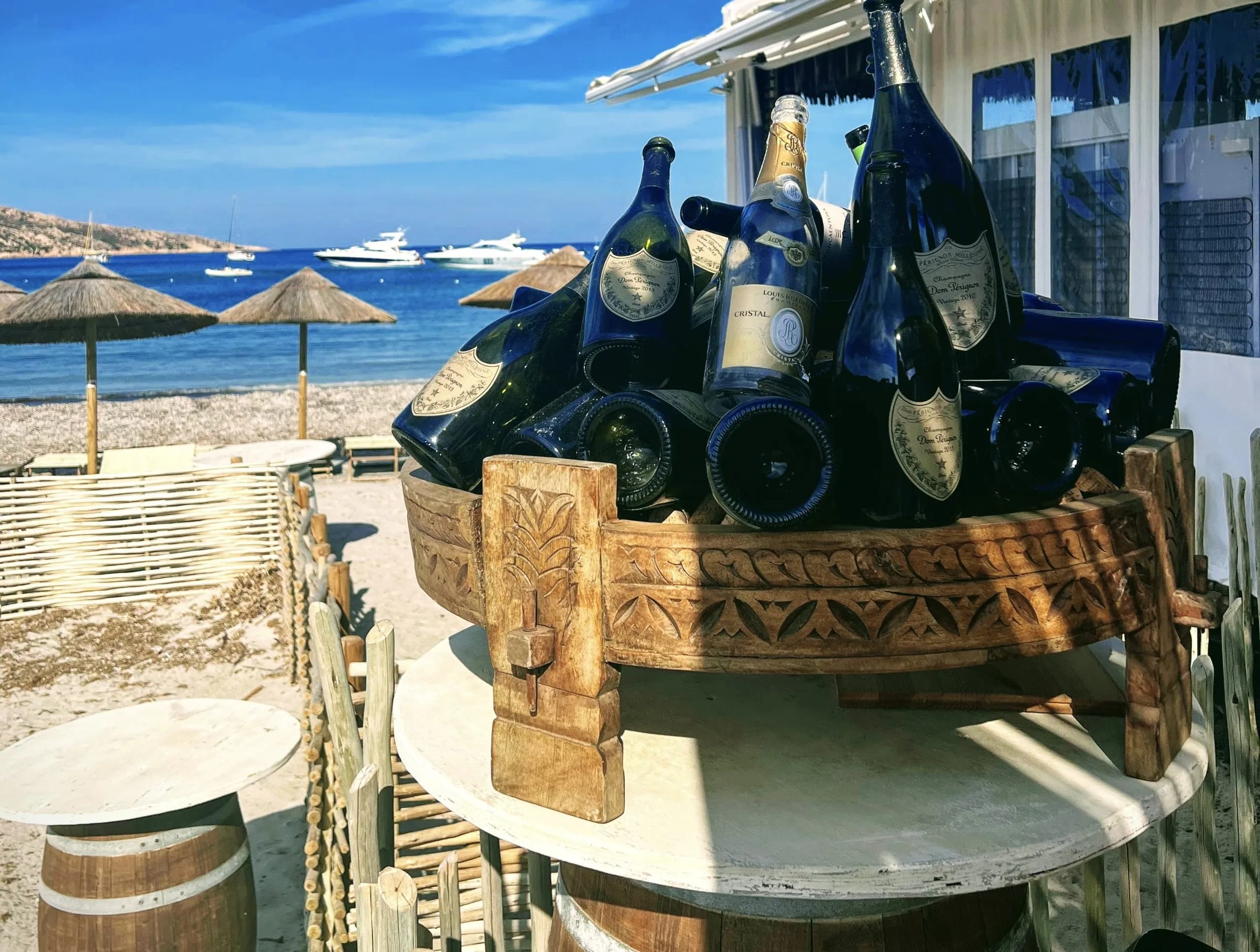 Champagne bottles on beach table with yachts