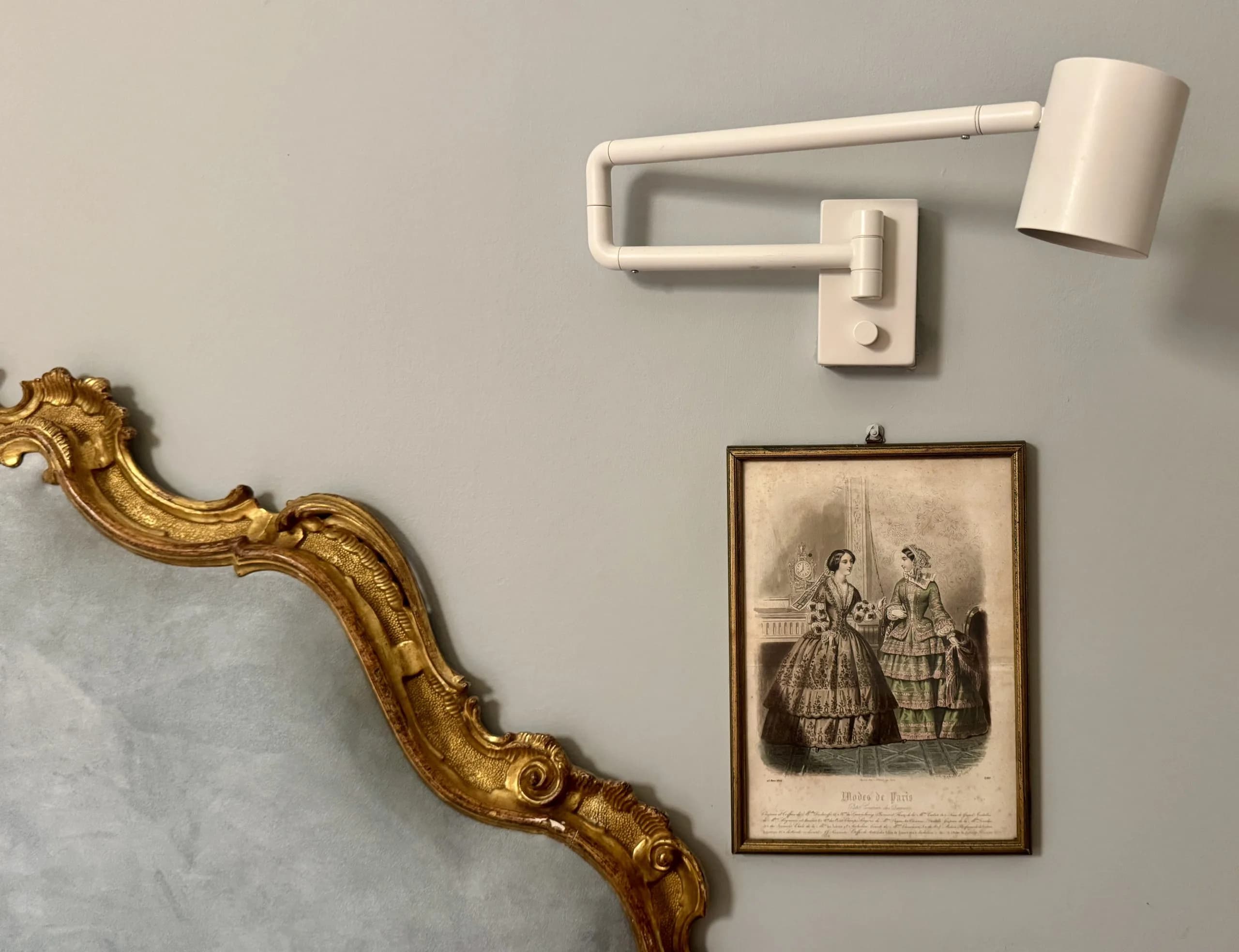 Wall-mounted lamp above vintage framed fashion print