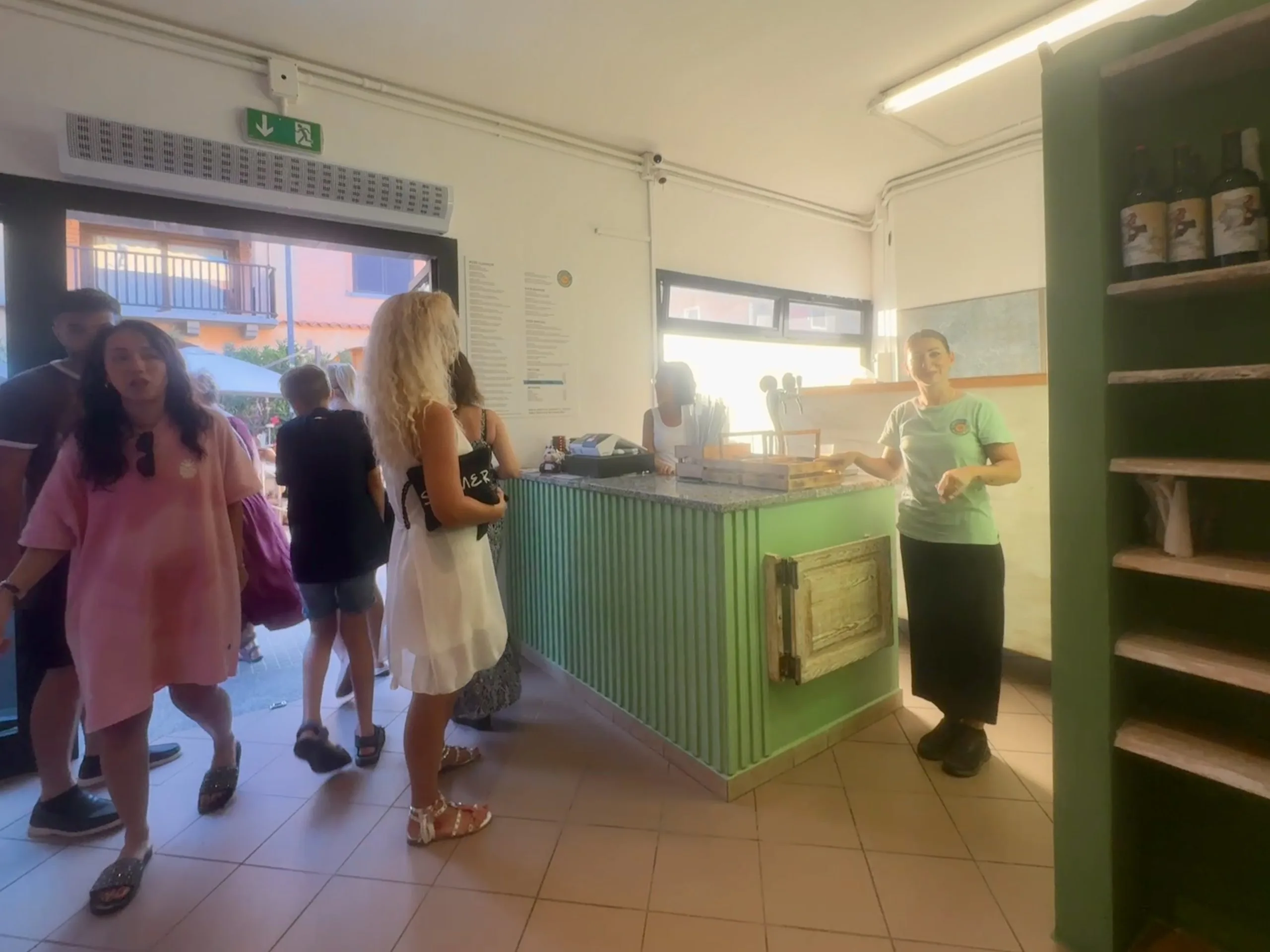 Clienti che entrano in un piccolo caffè con bancone verde