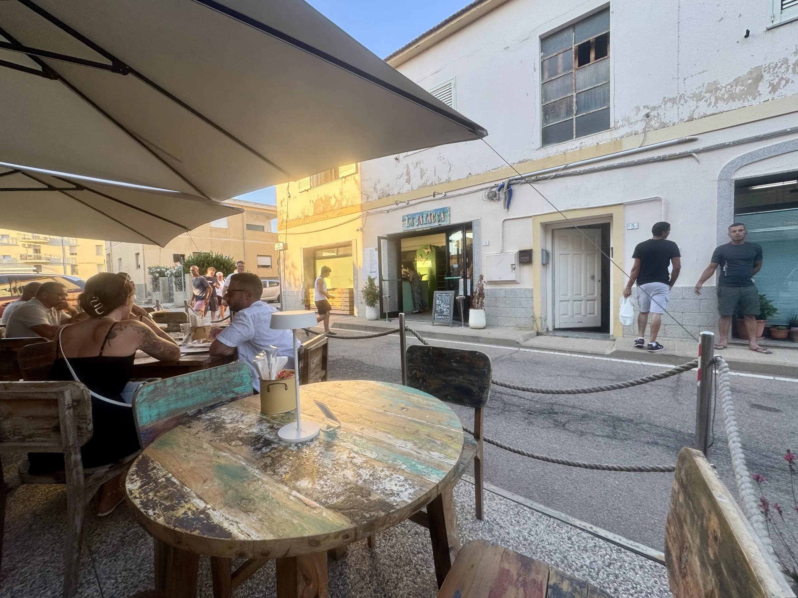 Caffè all'aperto con tavoli rustici su una via soleggiata