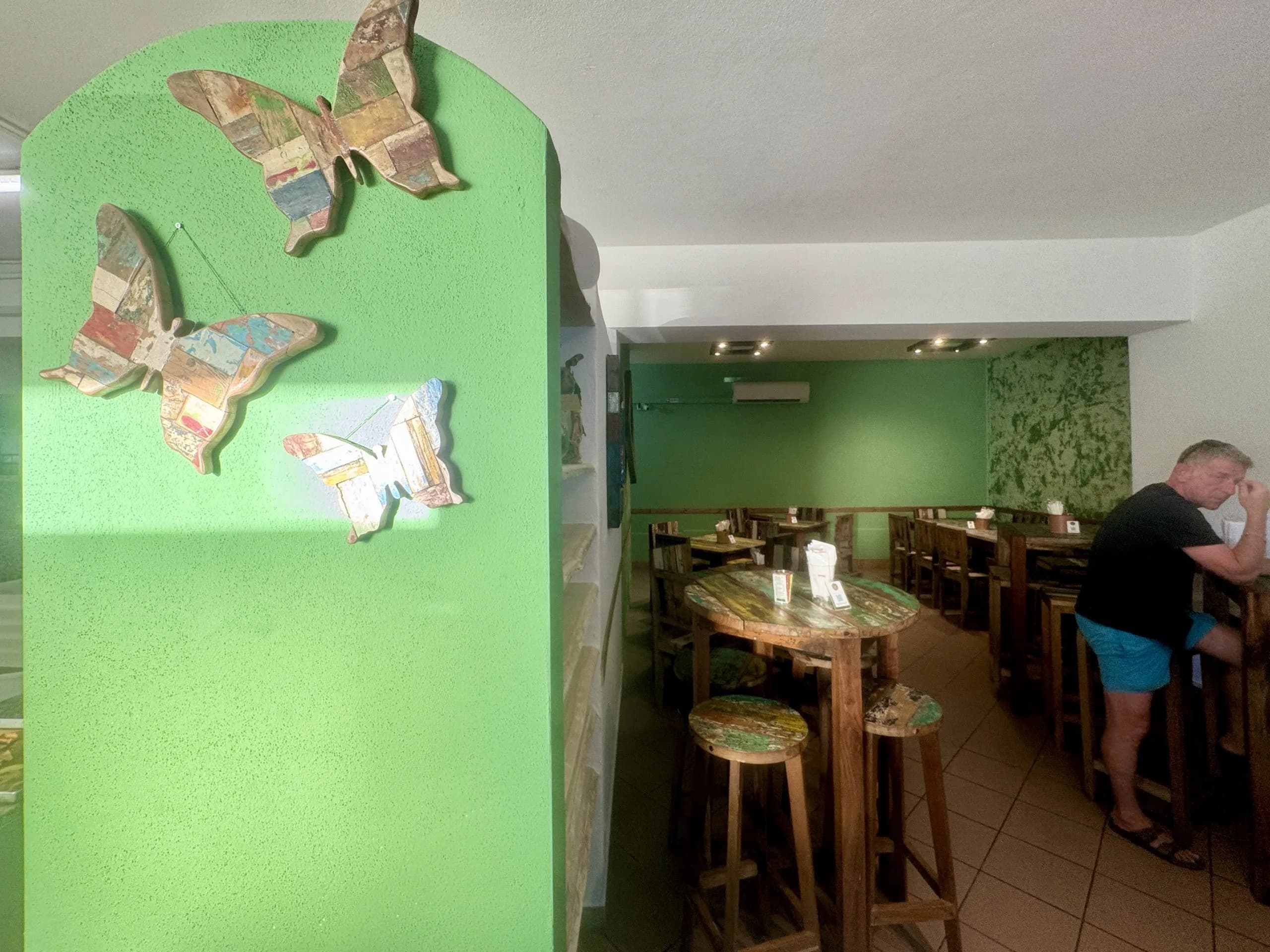 Interno rustico di ristorante con pareti verdi e decorazioni a farfalla