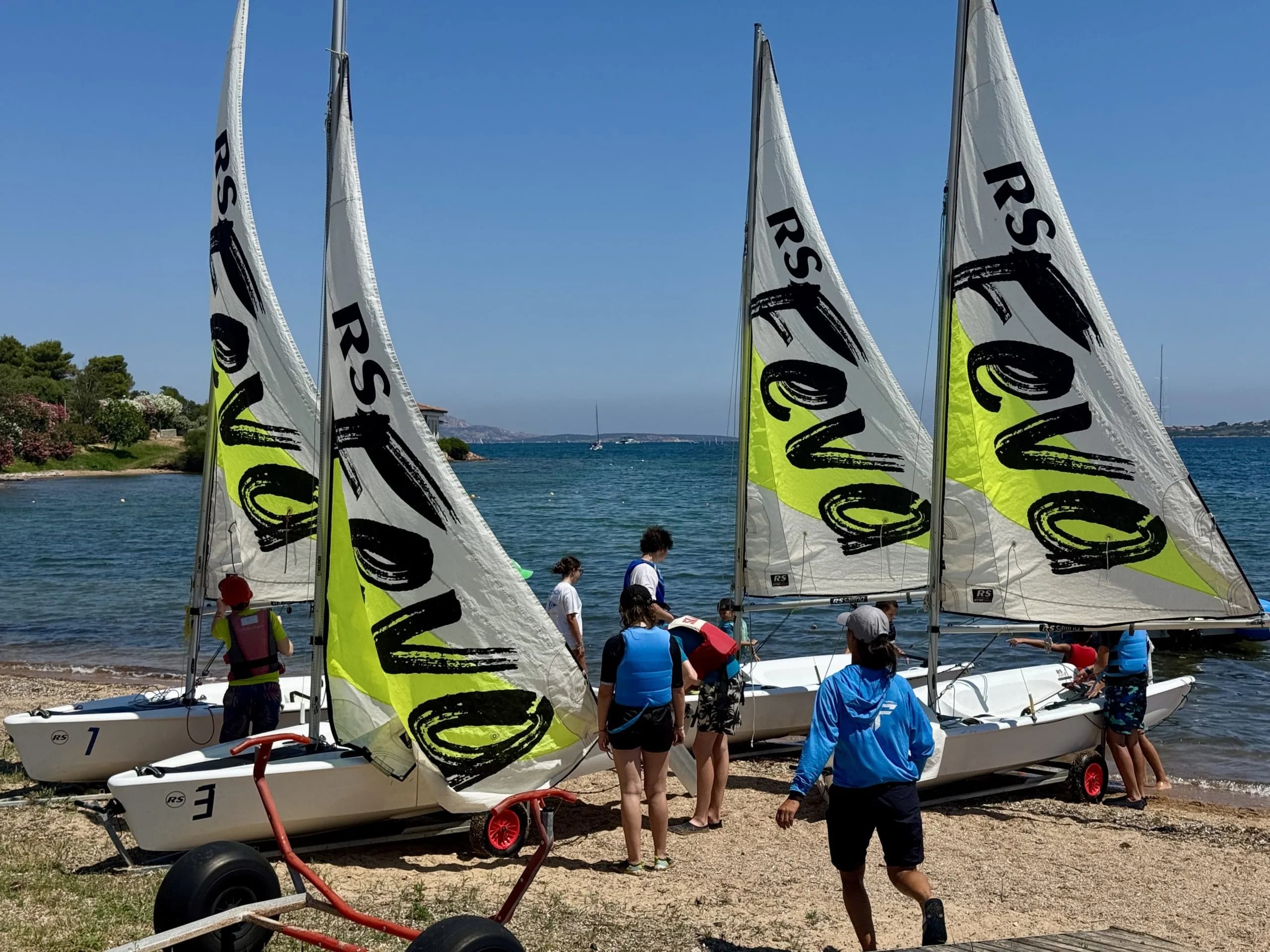 Youth sailors preparing small boats on sunny beach