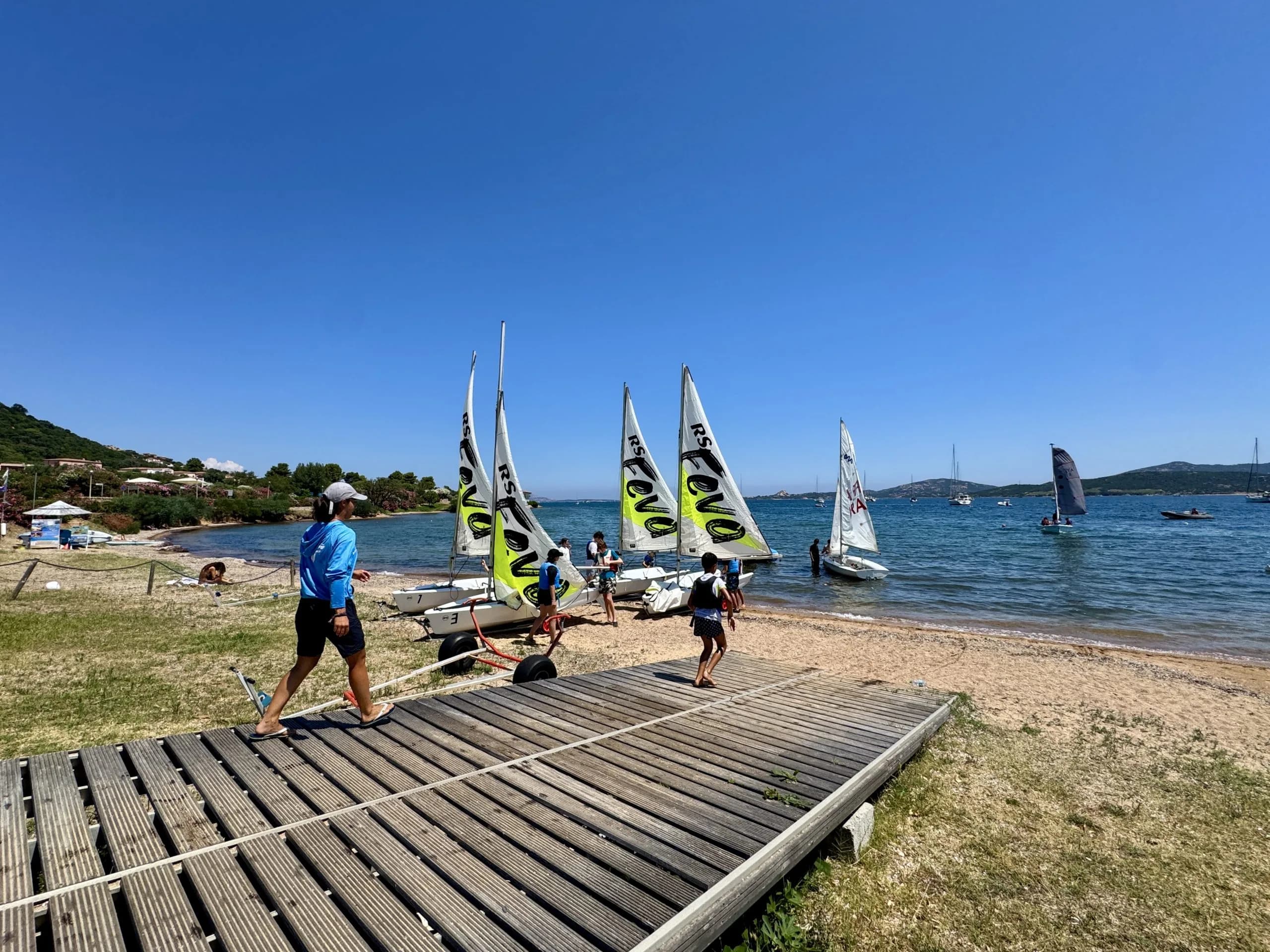 Children preparing small sailboats on sunny beach