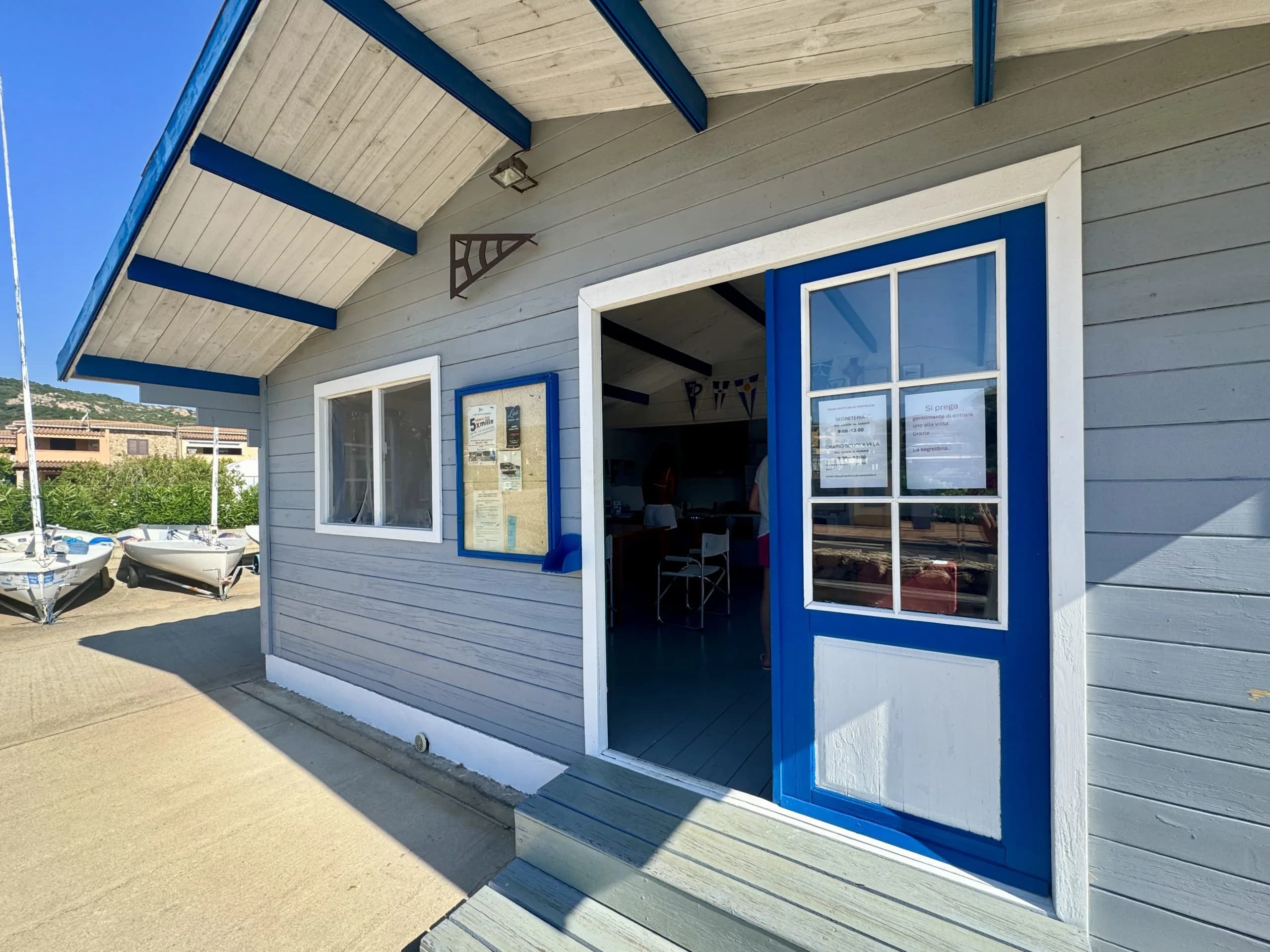 Small seaside sailing club building with boats outside