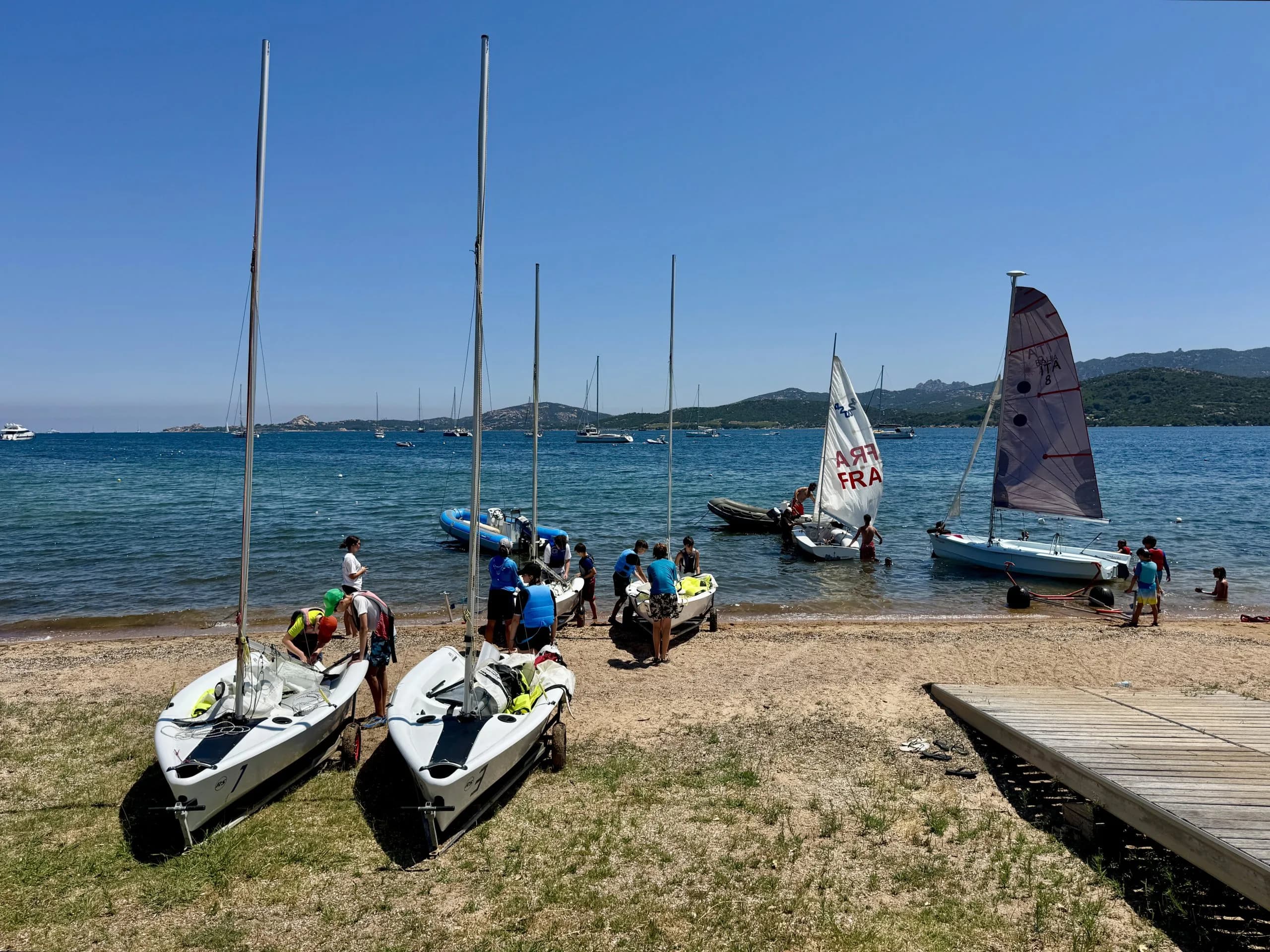 Children preparing sailboats on sunny beach shoreline