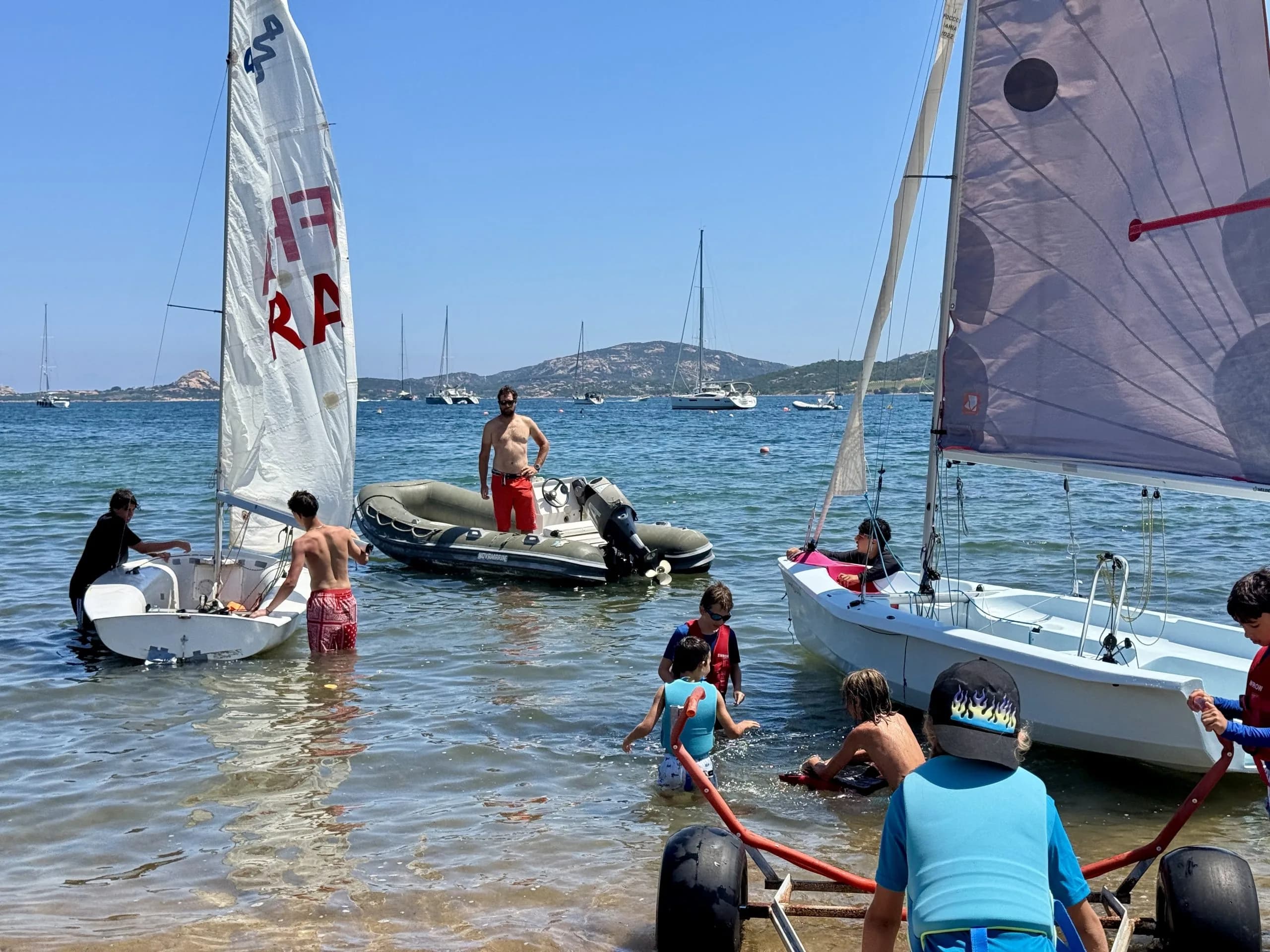 Children learning to sail at sunny beach