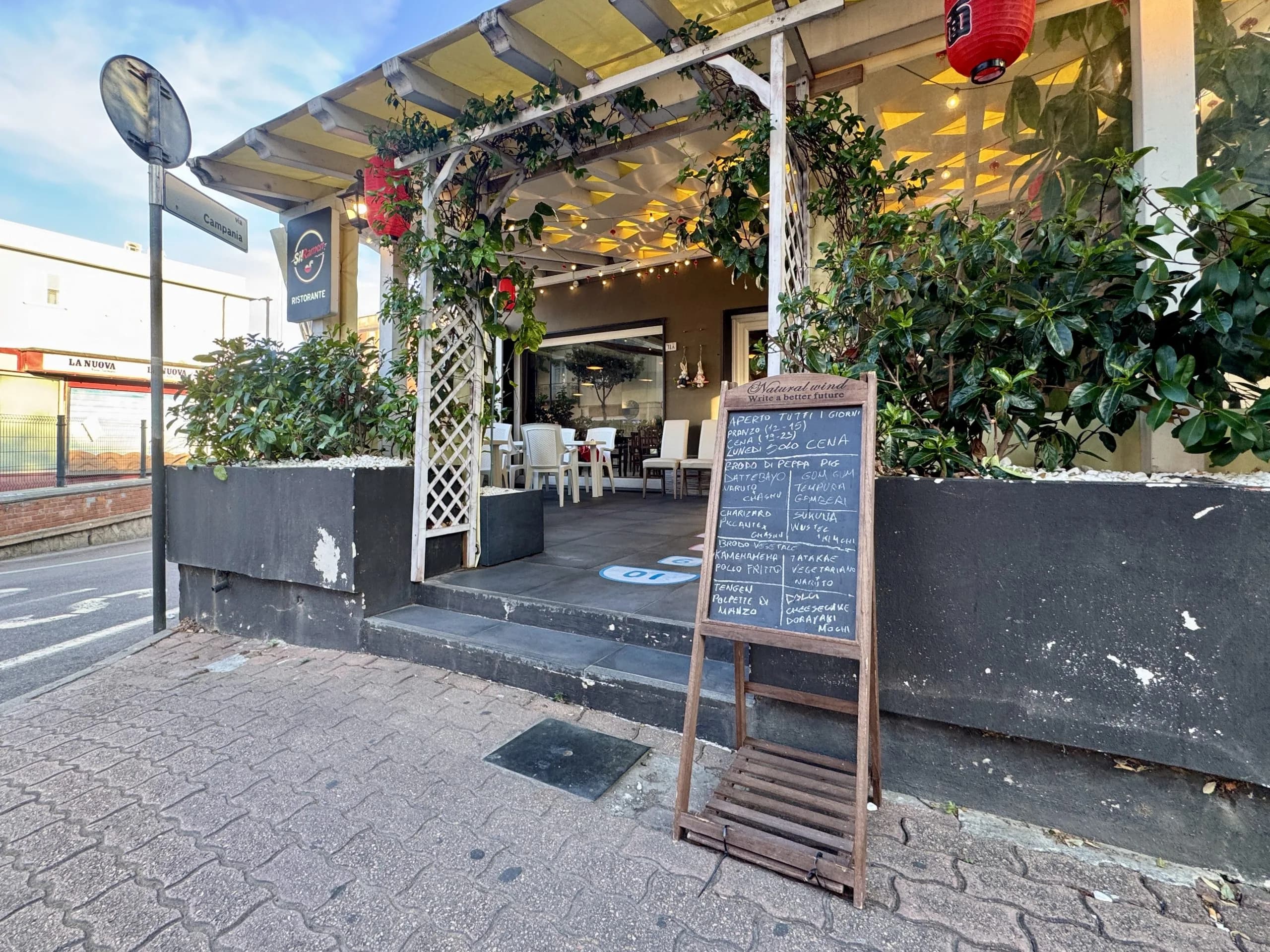 Gemütlicher Restauranteingang mit Pergola und Kreidetafel-Menü