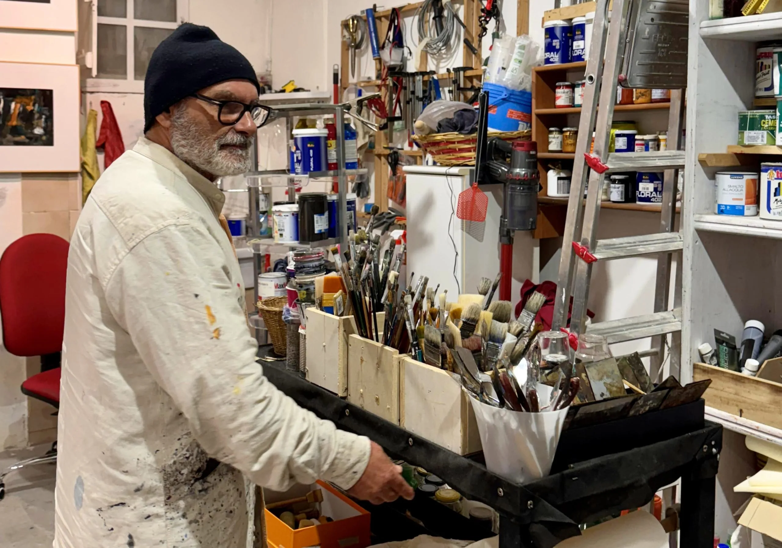 Artist in studio surrounded by brushes and paints