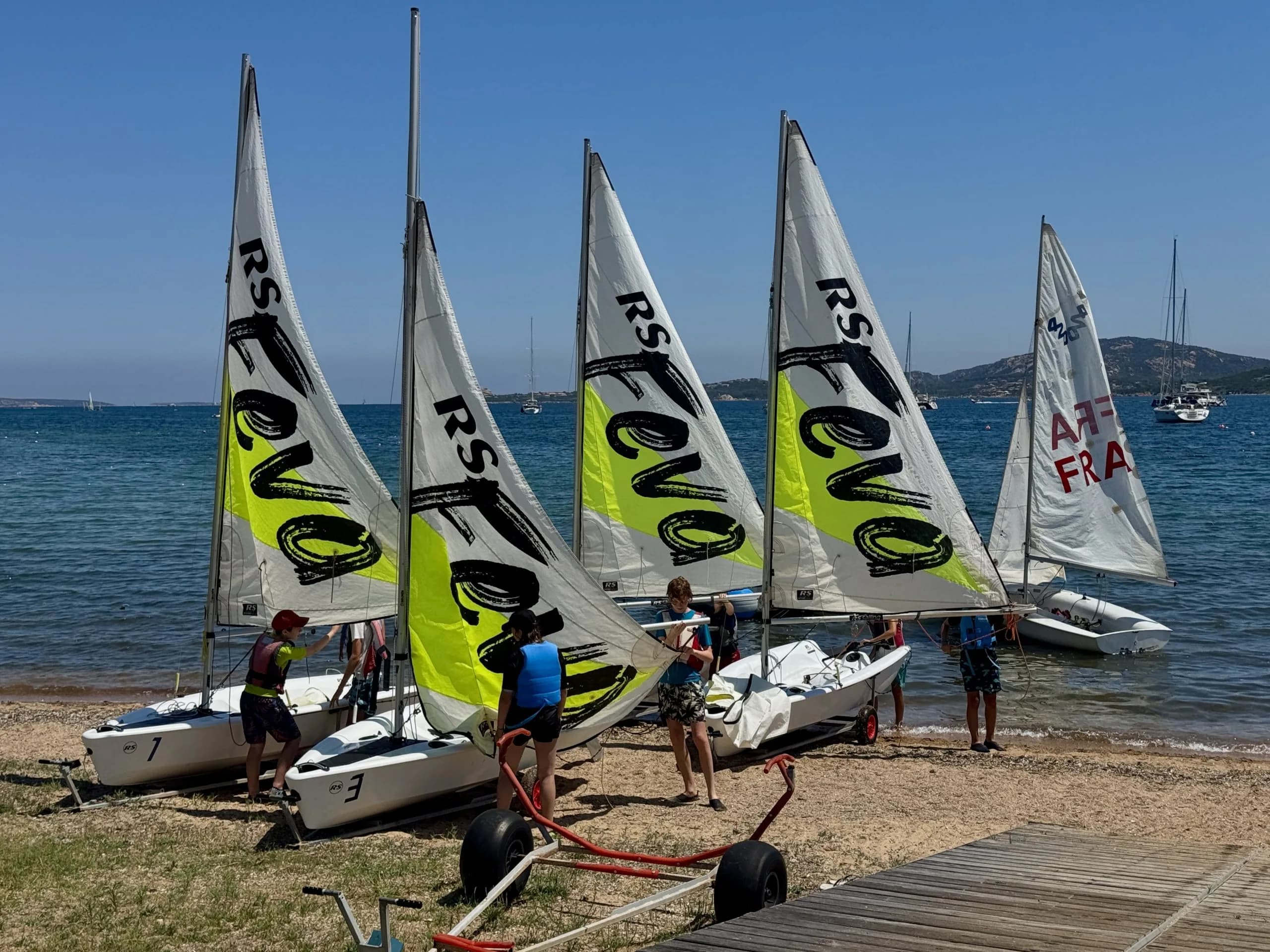 Children preparing small sailboats on sunny beach