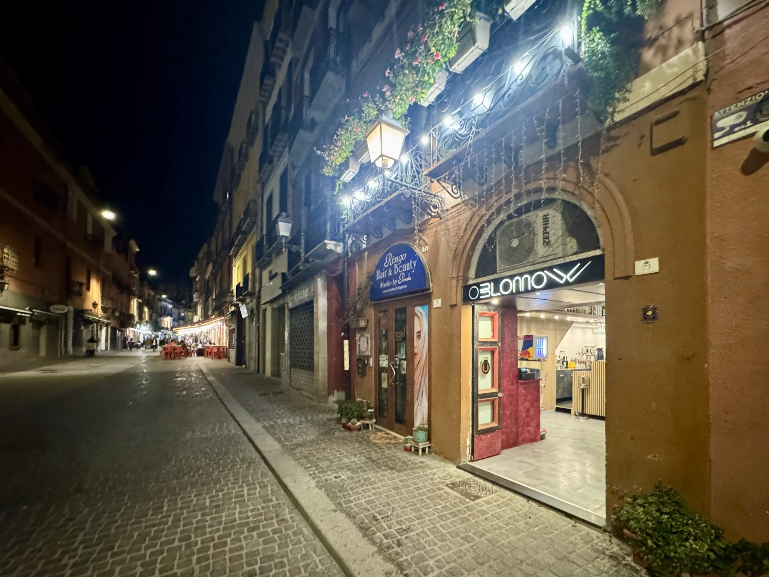 Charming cobblestone street with lit shops at night