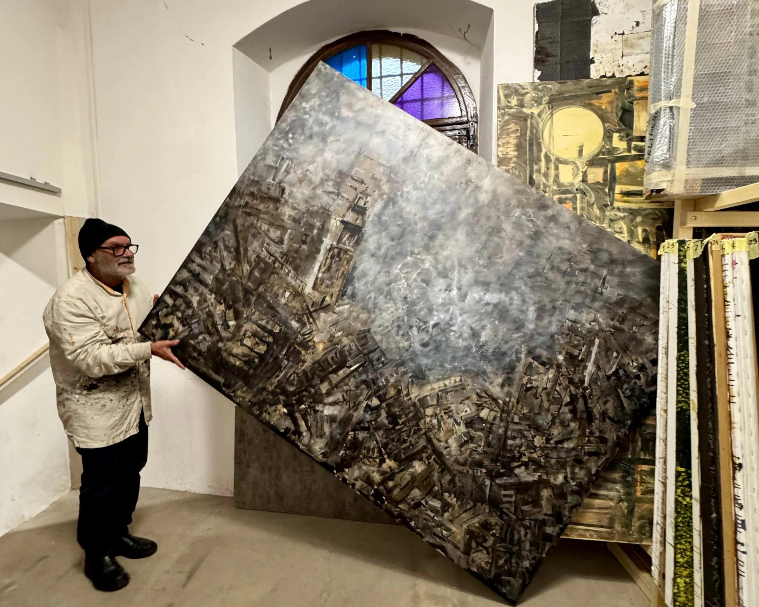 Artist holding large abstract painting in studio