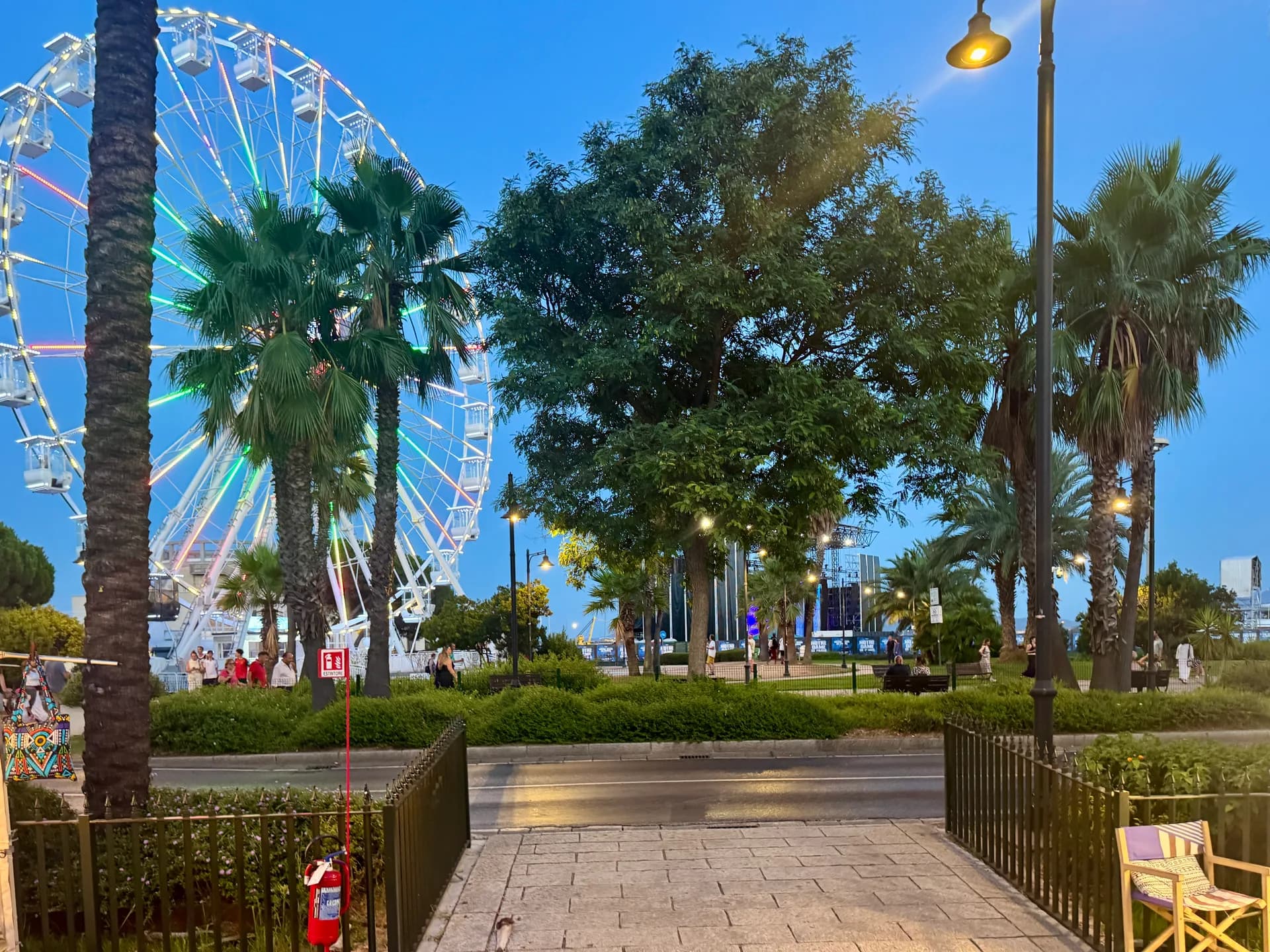 Molo Brin waterfront promenade in Olbia with Ferris wheel, palm trees, green spaces and leisure seating along the harbour