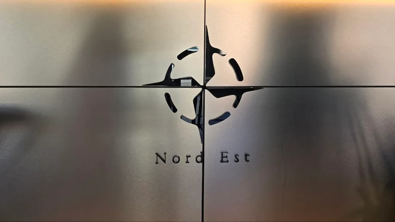 Nord Est restaurant sign in Olbia, featuring a Sardinian four moors-style compass logo etched into brushed metal panelling.