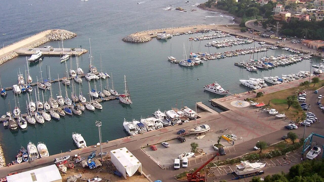 Aerial view of the Santa Maria Navarrese marina in Baunei, with moored sailing and motor boats and the coast beyond