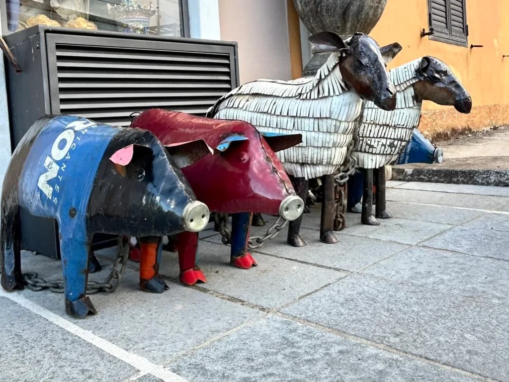 Whimsical animal sculptures made from recycled oil drums and scrap metal, displayed outside a shop in San Pantaleo, Gallura.