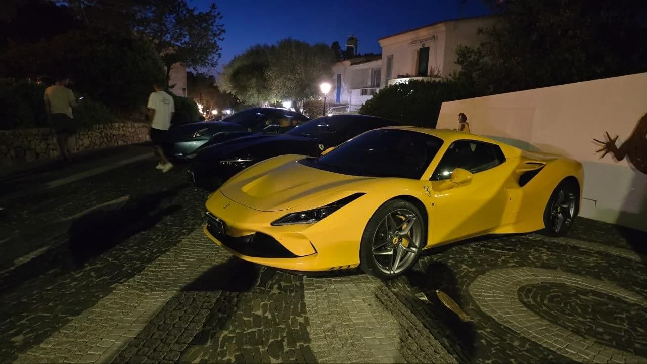 Yellow Ferrari Spider parked on a street in Porto Rotondo at night