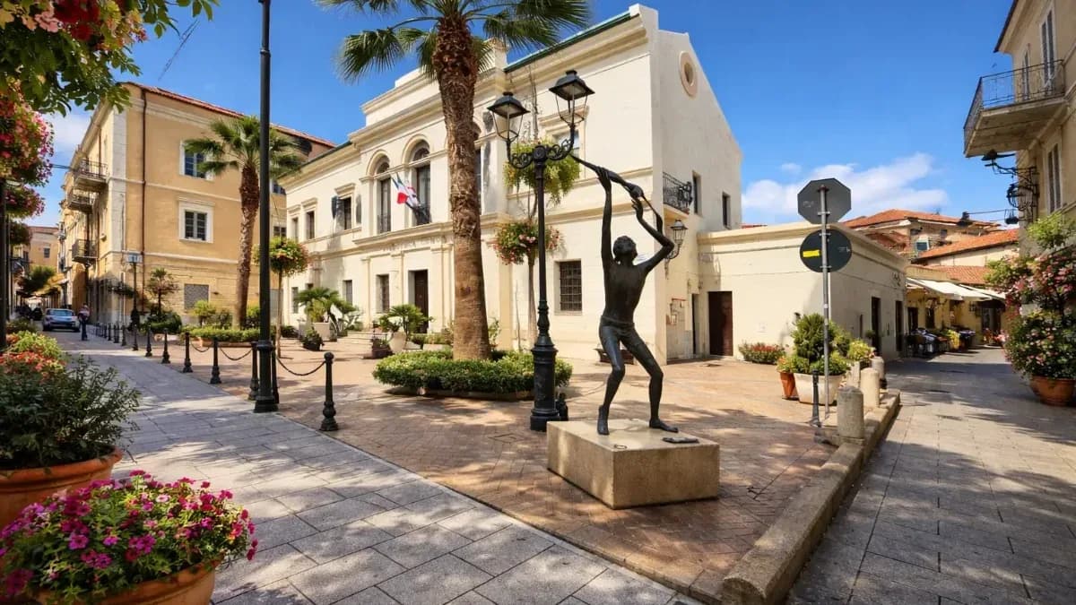 Corso Umberto I in Olbia's town centre, with the bronze Boy with the Seagull statue, palm trees and residential buildings