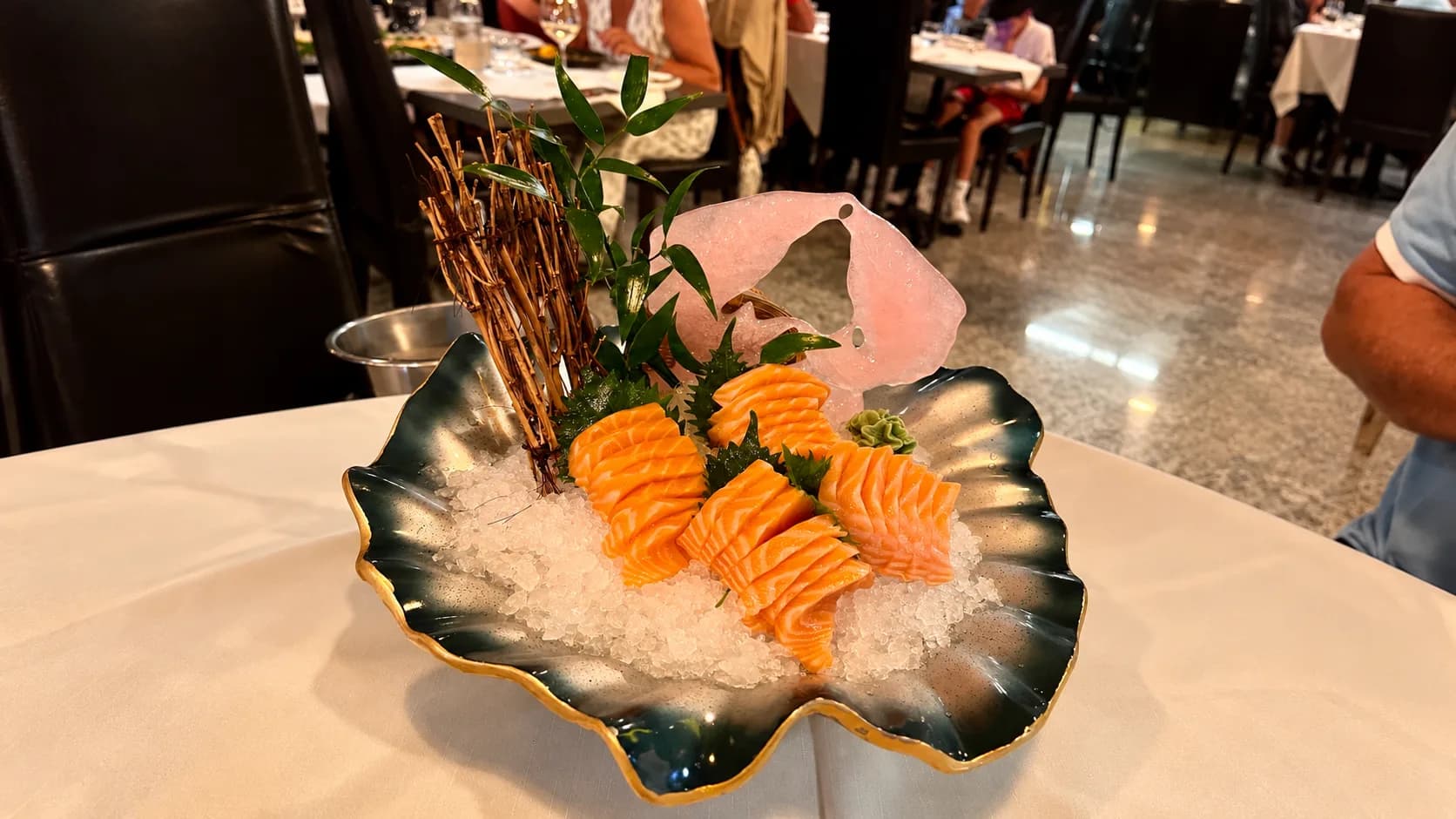 Salmon sashimi platter served on crushed ice with wasabi and decorative garnish at Kyoo Sushi restaurant, Sardinia.