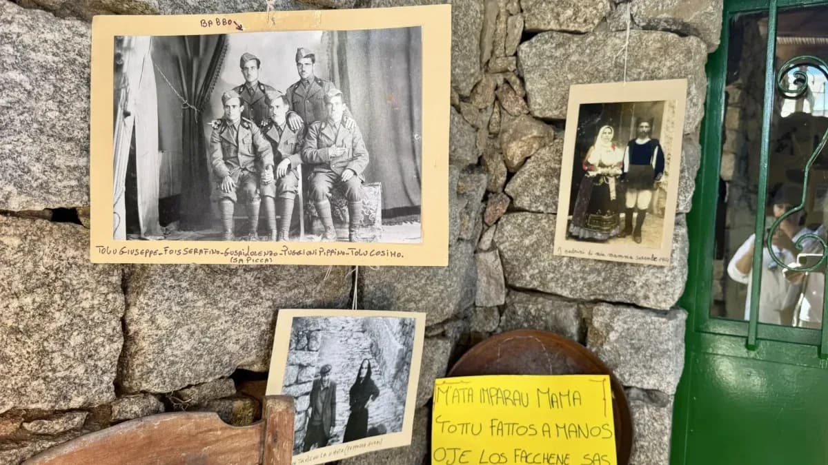 Vecchie fotografie di famiglia in bianco e nero appese a un muro di granito accanto a una porta verde a Lollove, in Barbagia